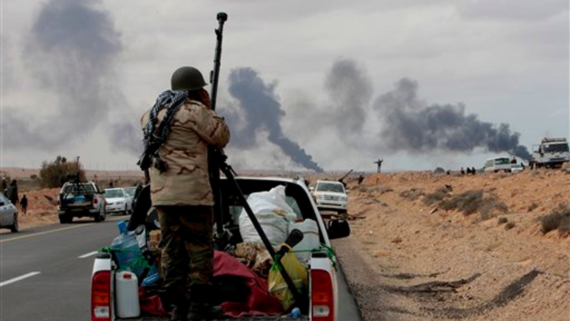 Anti-Libyan Leader Moammar Gadhafi rebel, stands behind his anti-aircraft machine gun as smokes rises from shell impacts in the distance during fighting against pro-Moammar Gadhafi forces, in Sedra, eastern Libya, on Wednesday March 9, 2011. Gadhafi appeared to be keeping up the momentum he has seized in recent days in his fight against rebels trying to move on the capital, Tripoli, from territory they hold in eastern Libya. (AP Photo/Hussein Malla)