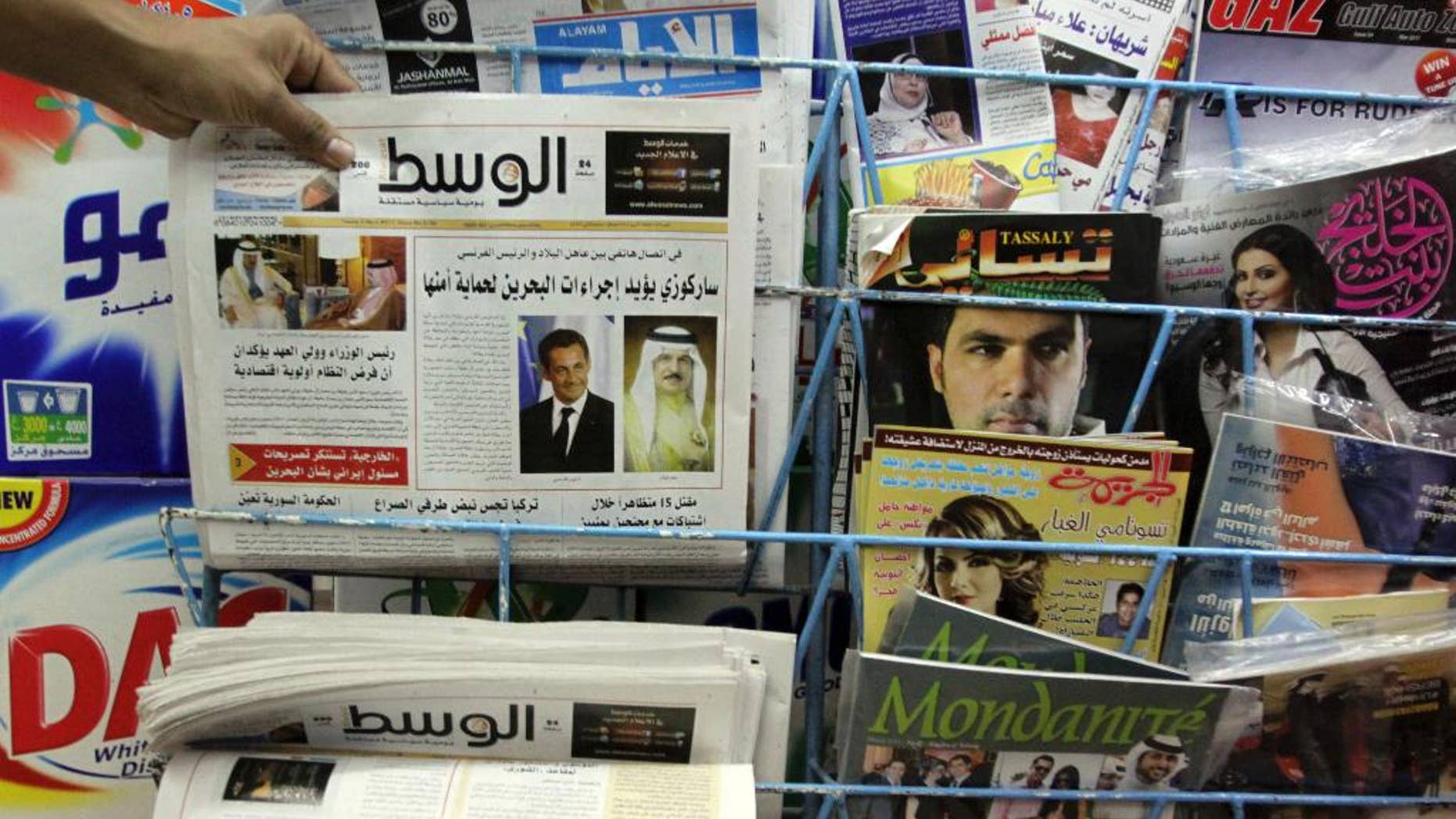 File - In this Tuesday, April 5, 2011, file photo, a man picks up a copy of Al Wasat newspaper at a newsstand in Hamad Town, Bahrain. Bahraini authorities have ordered the independent newspaper to stop publishing online Monday and say a city hall was set ablaze during clashes between opposition protesters and police. The suspension of Al-Wasat’s online operations followed a spike in anti-government protests led by the country’s Shiite majority that began Saturday. (AP Photo/Hasan Jamali, File)