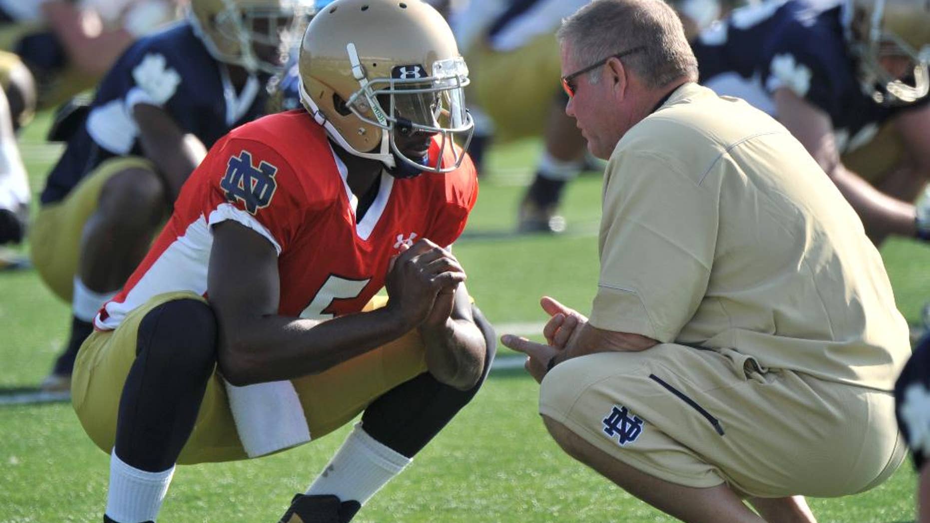 FILE - In this Aug. 9, 2014, file photo, Notre Dame coach Brian Kelly, right, talks with quarterback Everett Golson during practice in South Bend, Ind. Golson has reclaimed the job as Notre Dame's starting quarterback after being suspended last semester for academic impropriety. Coach Brian Kelly on Wednesday, Aug. 13, 2014, said Golson would start against Rice on Aug. 30 and said he hopes he will be the starter for the entire season. (AP Photo/Joe Raymond, FILE)