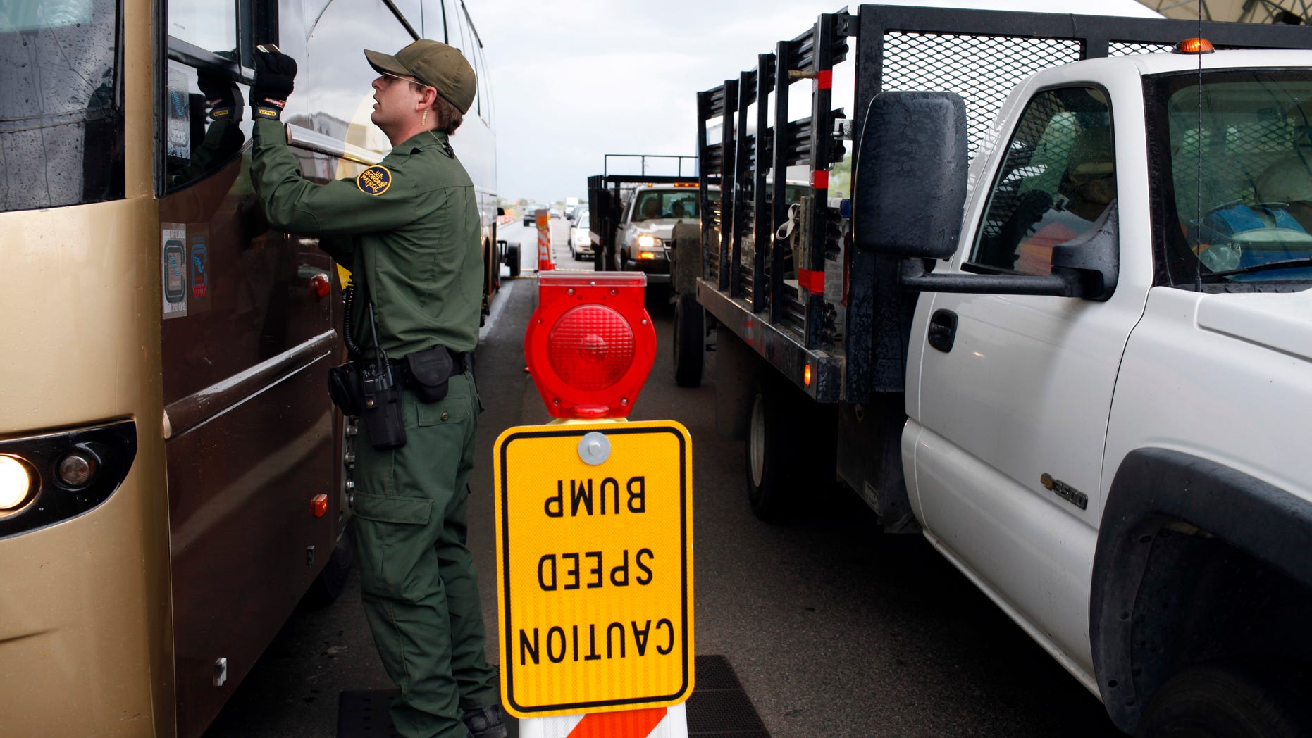 FILE - This July 29, 2010 file photo shows a Border Patrol agent checking the identification card of a bus driver at a checkpoint in Amado, Ariz. The American Civil Liberties Union reported Wednesday Jan. 15, 2014 that border patrol agents at checkpoints across southern Arizona are routinely violating the constitutional rights of U.S. residents, including unjustified detentions and illegal searches as a pretext to investigating other criminal activity in violation of the agency's mandate that stops be limited to inquiring about citizenship and visually inspecting vehicles. (AP Photo/Jae C. Hong, file)