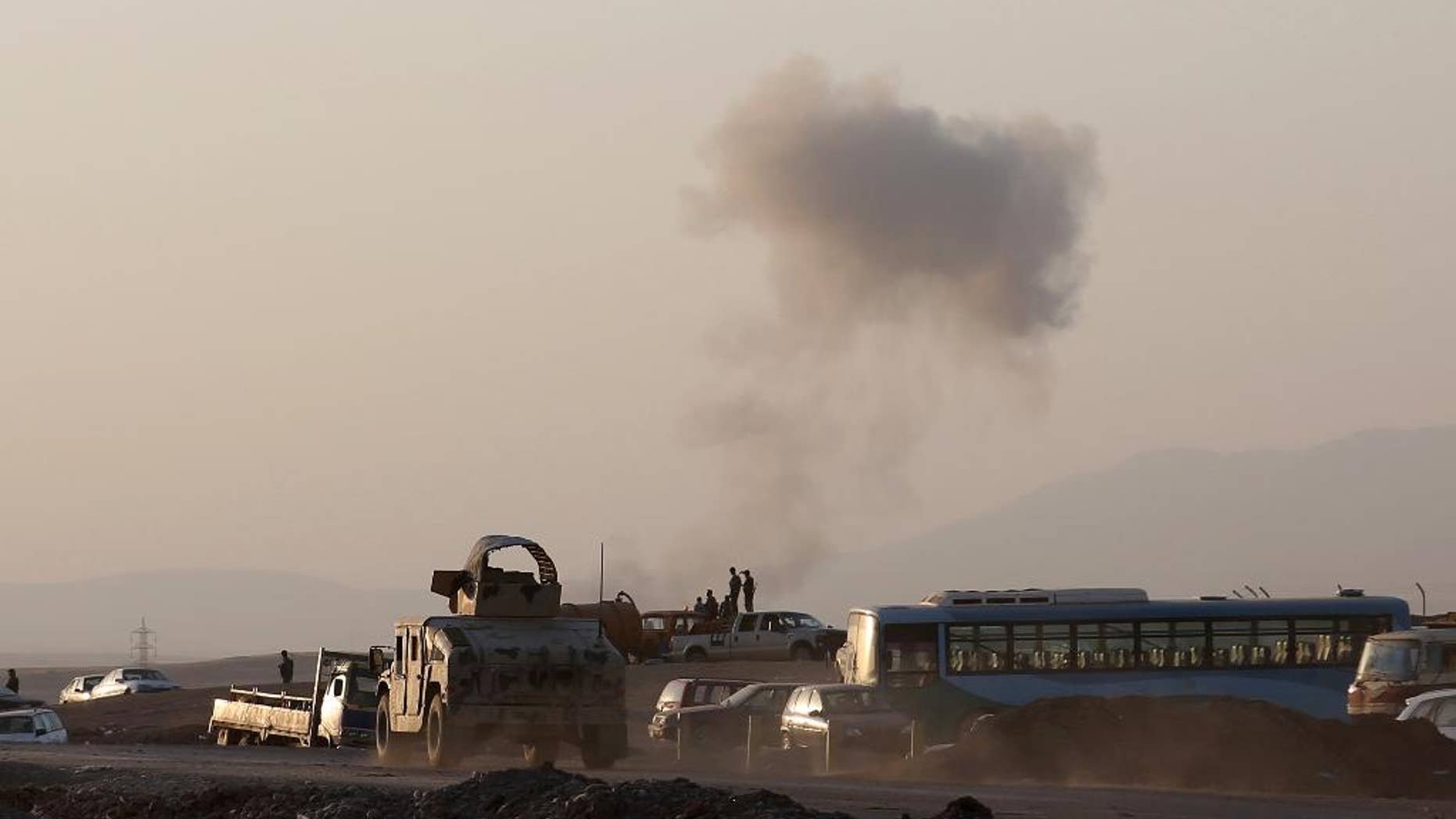 FILE - In this Aug. 8, 2014 file photo, an armored vehicle belonging to Kurdish Peshmerga fighters rushes to a bombing site as smoke rises after airstrikes targeting Islamic State militants near the Khazer checkpoint outside of the city of Irbil in northern Iraq. The airstrikes were launched outside the Kurdish regional capital Irbil, and marked the first time U.S. forces have directly targeted the extremist Islamic State group, which controls large areas of Syria and Iraq. The death last week of a Canadian soldier, reportedly killed by friendly fire from Kurdish troops near the northern village of Bashiq, has put the spotlight once again on the dangers that U.S. troops could face in Iraq. (AP Photo/ Khalid Mohammed, File)