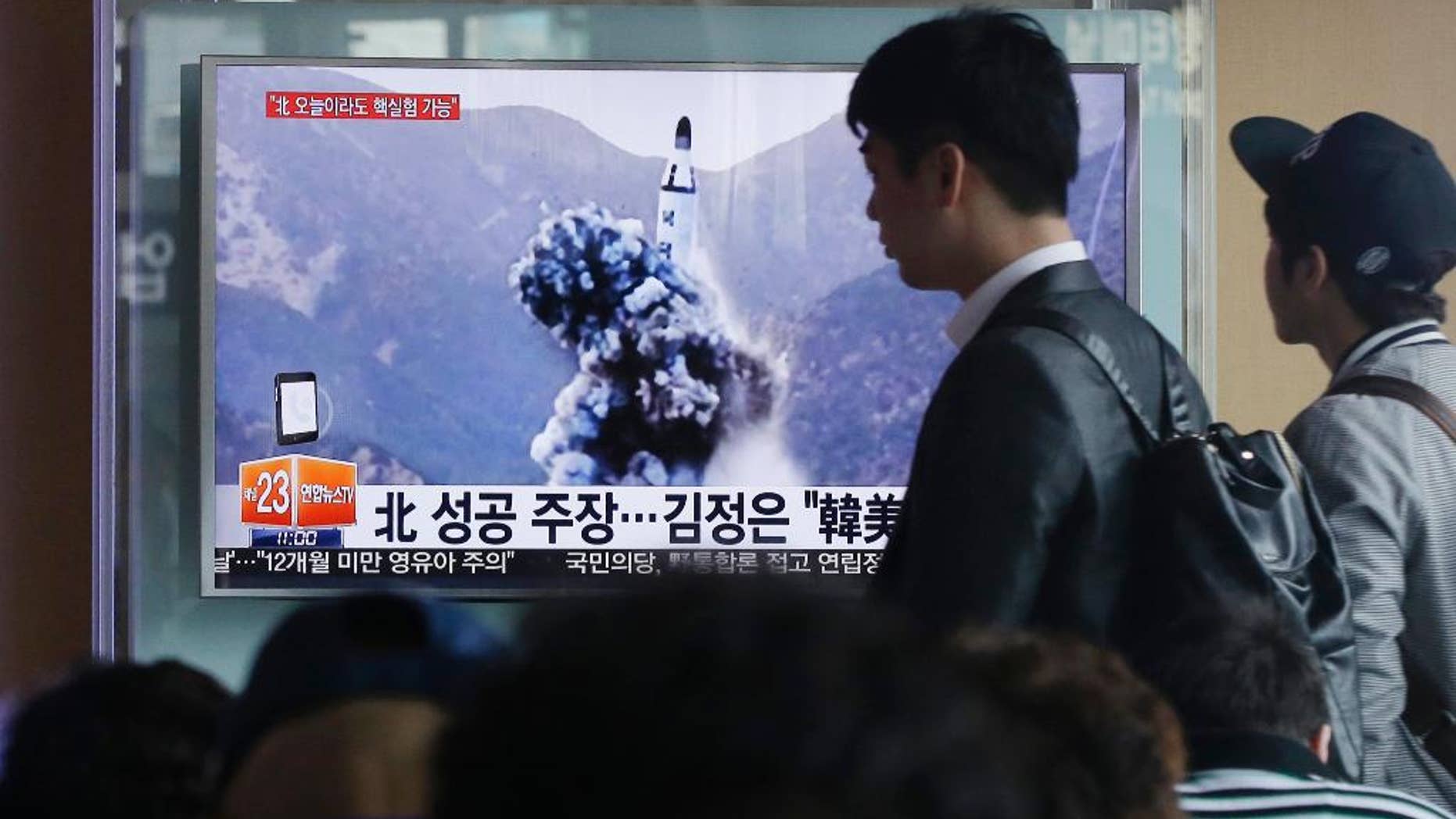 FILE - In this April 24, 2016 file photo, a man walks by as people watch a TV news program showing an image published earlier in the day in North Korea's Rodong Sinmun newspaper of North Korea's ballistic missile that the North claimed to have launched from underwater, at Seoul Railway station in Seoul, South Korea. With Donald Trump getting ready to become president, North Korea is talking about launching an ICBM and Washington officials are saying they will shoot down anything that threatens the territory of the U.S. or its allies. (AP Photo/Ahn Young-joon, File)