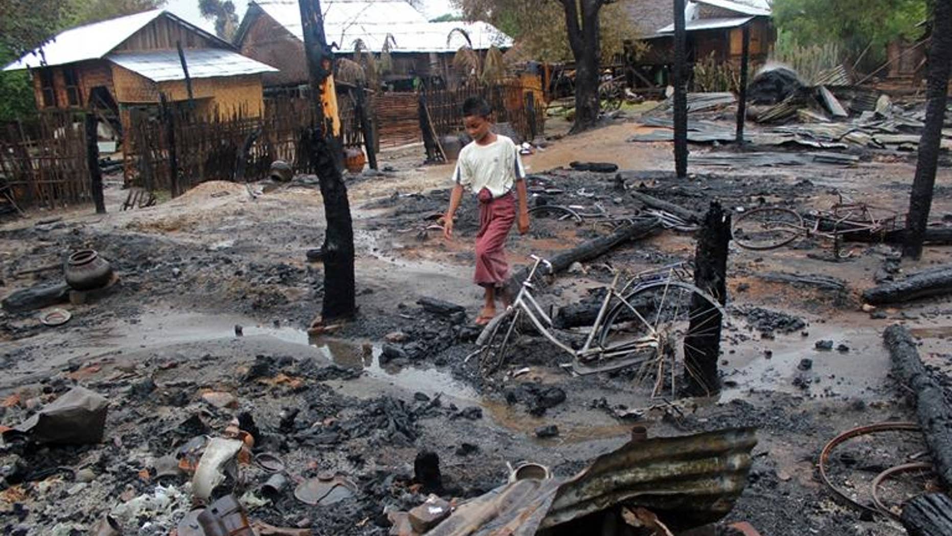 A Muslim boy walks through the charred remains of houses in Htan Gone village on August 26, 2013, after some 1,000 anti-Muslim rioters rampaged through villages in Kanbalu township in Myanmar.