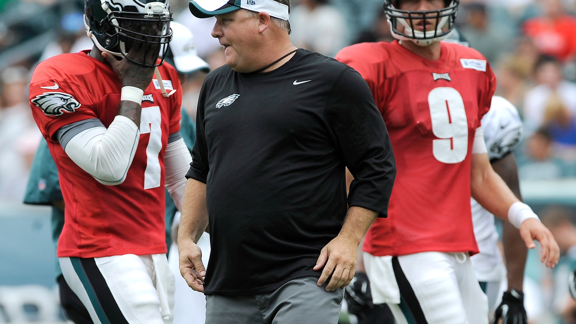 FILE - In this July 28, 2013, file photo, Philadelphia Eagles coach Chip Kelly, center, calls out a play as Michael Vick (7) and Nick Foles line up at NFL football training camp in Philadelphia. Despite Kelly's insistence that the Eagles run the same offense whether it's Vick or Foles under center, the two quarterbacks have obvious differences. (AP Photo/Michael Perez, File)