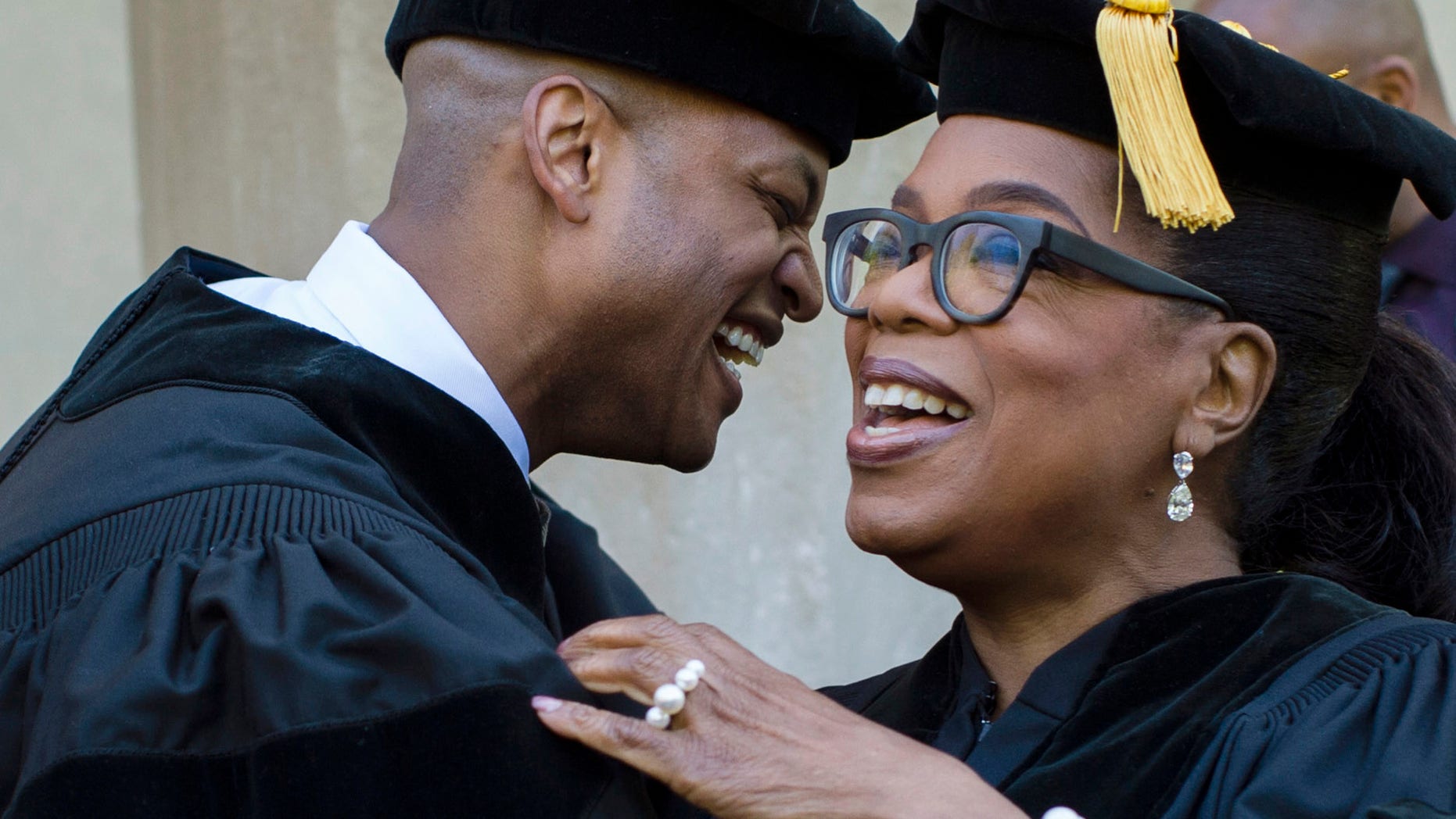 In this photo provided by Skidmore College, author Wes Moore embraces Oprah Winfrey at Skidmore College's 106th Commencement, Saturday, May 20, 2017 at the Saratoga Performing Arts Center, in Saratoga Springs, N.Y. The author, actress and former talk show host spoke at the graduation. (Erin Covey/Skidmore College via AP)