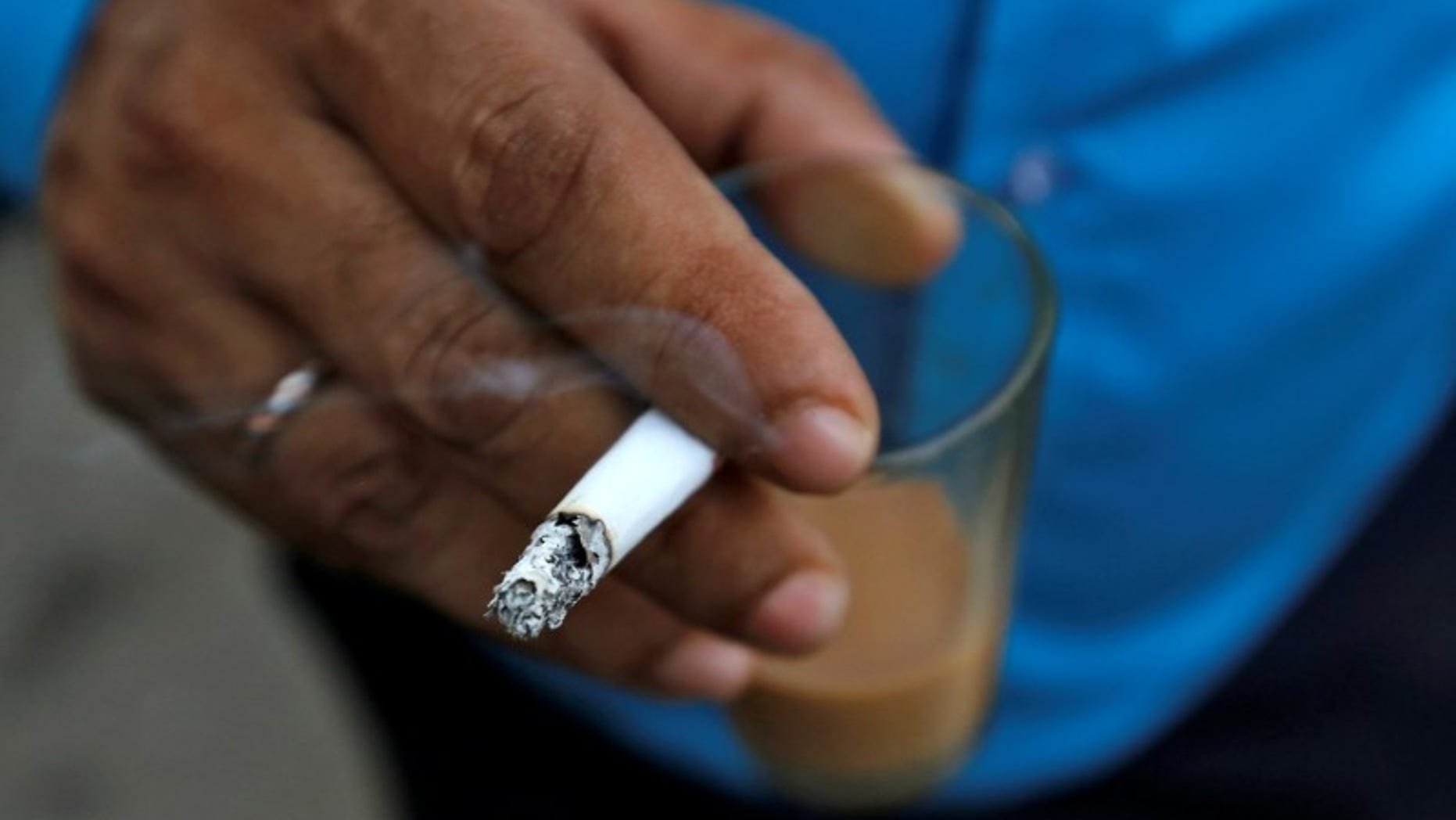 A man smokes a cigarette along a road in Mumbai