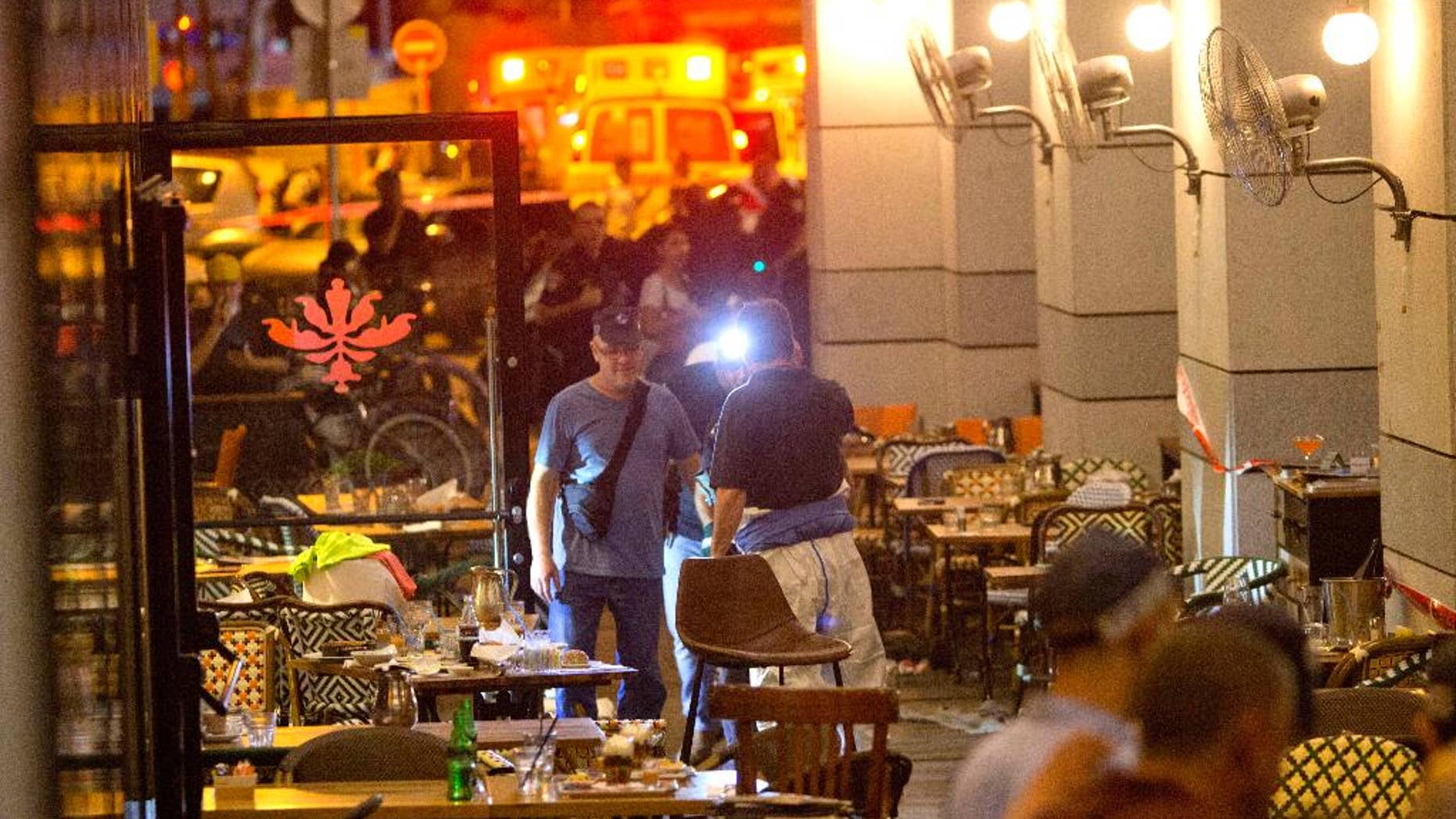Israeli police officers examine the scene of a shooting attack in Tel Aviv, Israel, Wednesday, June 8, 2016. Two Palestinian gunmen opened fire in central Tel Aviv Wednesday night, killing three people and wounding at least five others, Israel police said. (AP Photo/Sebastian Scheiner)