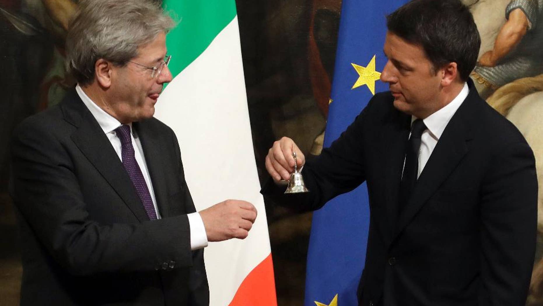 Italian outgoing Premier Matteo Renzi, right, hands over the cabinet minister bell to new Premier Paolo Gentiloni during the handover ceremony at Chigi Palace Premier's office, in Rome, Monday, Dec. 12, 2016. Paolo Gentiloni, a Democrat serving as foreign minister, formed Italy’s new government Monday, keeping several key ministers from the coalition of Matteo Renzi, who resigned last week. (AP Photo/Gregorio Borgia)