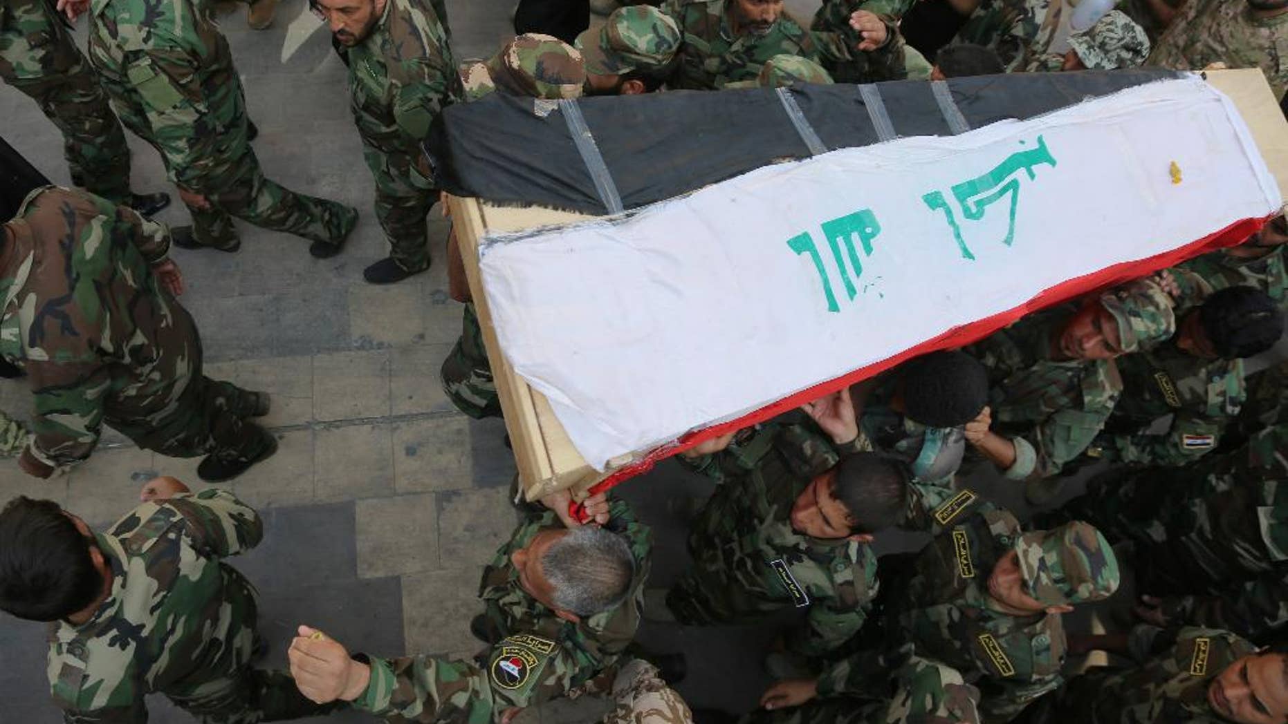 Shiite militiamen carry the flag-draped coffin of their colleague who was killed during clashes with Islamic militants in the town of Amirli, Iraq, on Wednesday, during his funeral procession in the Shiite holy city of Najaf, 100 miles (160 kilometers) south of Baghdad, Iraq, Thursday, Sept. 4, 2014. The Islamic State group has carved out a self-styled caliphate in the large area straddling the Iraqi-Syrian border that it now controls. In early August, the United States launched air strikes on the militant group in Iraq, in an effort to help Iraqi forces fight back against the growing militant threat. (AP Photo/Jaber al-Helo)