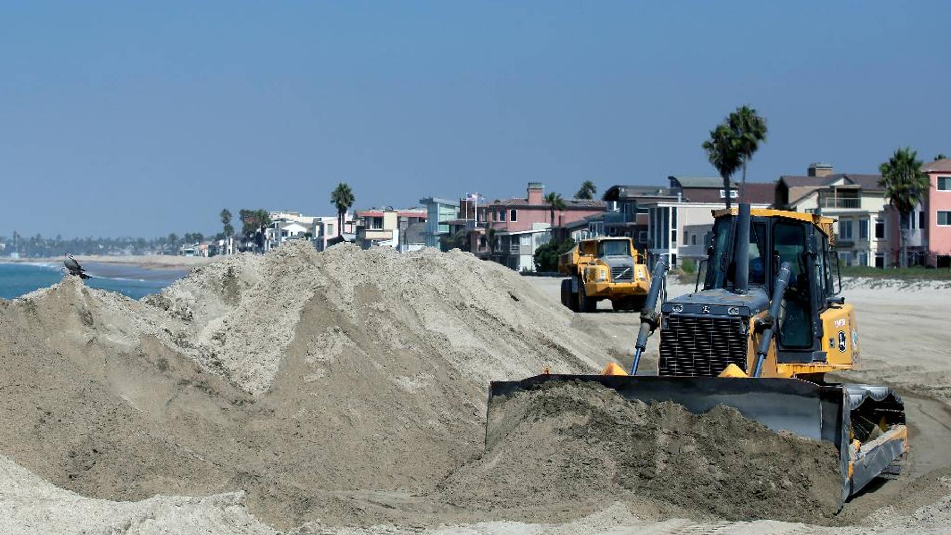 A bulldozer works to pile sand on a temporary berm to protect beach front homes on, Friday, Sept. 5, 2014, in Long Beach, Calif. Southern California is in for another round of high surf generated by what is currently Hurricane Norbert in the Pacific Ocean off Baja California. (AP Photo/Chris Carlson)