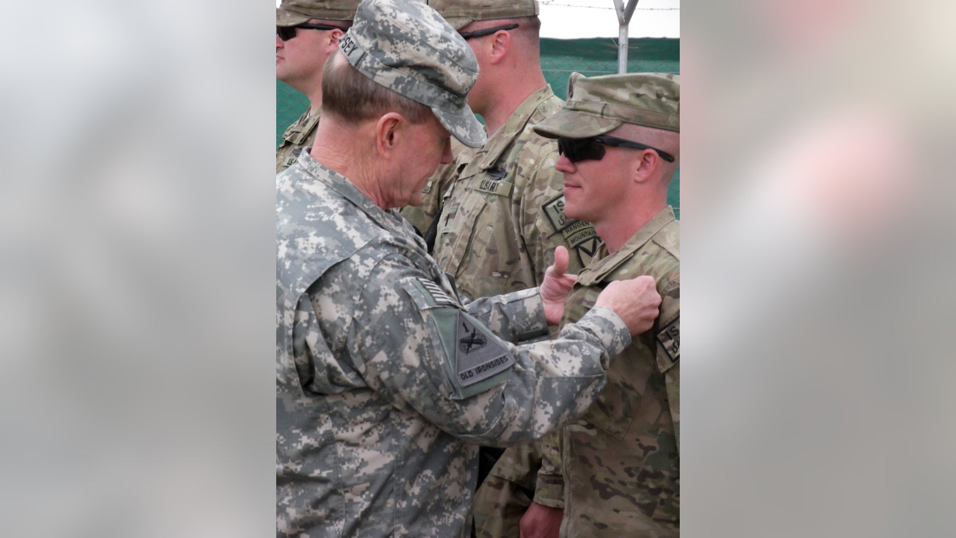 U.S. Chairman of the Joint Chiefs of Staff, Gen. Martin Dempsey, pins a Combat Infantrymen Badge on an unidentified soldier at Forward Operating Base Sharana in Afghanistan's Paktika province during his visit to the base Sunday, April 7, 2013. (AP Photo/Robert Burns)