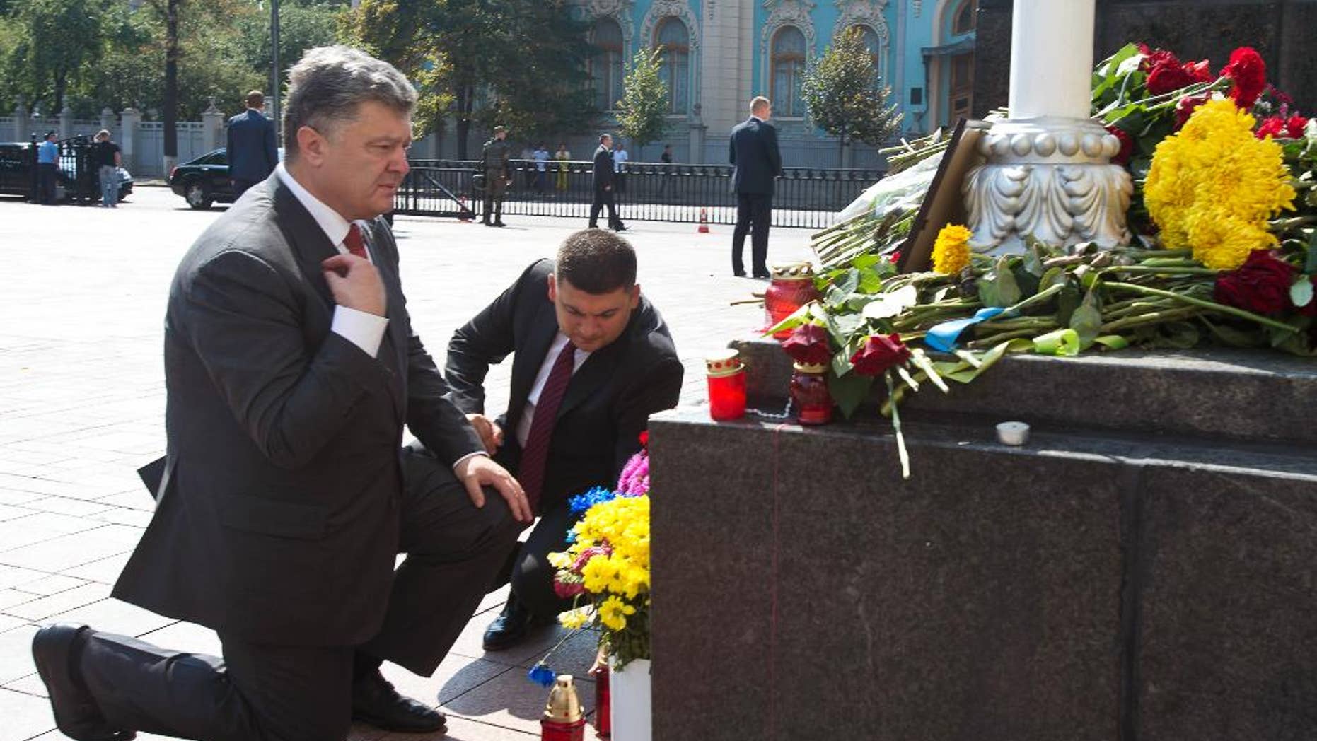 Ukraine's President Petro Poroshenko, left, and parliament speaker Volodymyr Groisman lay flowers by the photo of a police officer who was killed in a Monday clash, in front of Parliament in Kiev, Ukraine, Tuesday, Sept. 1, 2015. Ukrainian police say 141 people remain hospitalized after a nationalist protest in Kiev turned violent, with 10 of the injured in serious condition. Two officers died from their wounds. (Anastasiia Sirotkina, Pool photo via AP)