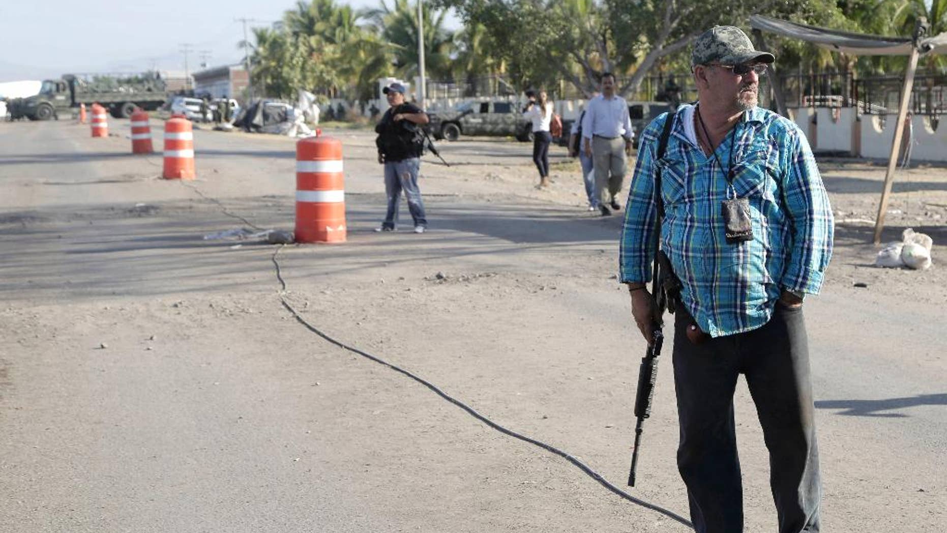 FILE - In this Dec. 17, 2014, file photo, the leader of a local self-defense group, Hipolito Mora, right, stands armed at the entrance of the town of La Ruana, a day after a clash between two rival "self-defense" groups outside of the town, in the state of Guerrero, Mexico. Federal security commissioner in Michoacan, Alfredo Castillo said Tuesday Dec. 30, 2014, that two leaders and nearly three dozen members of rural self-defense forces in the western state of Michoacan who were involved in Dec. 17 clash, have turned themselves in to authorities. (AP Photo/Gustavo Aguado, File)