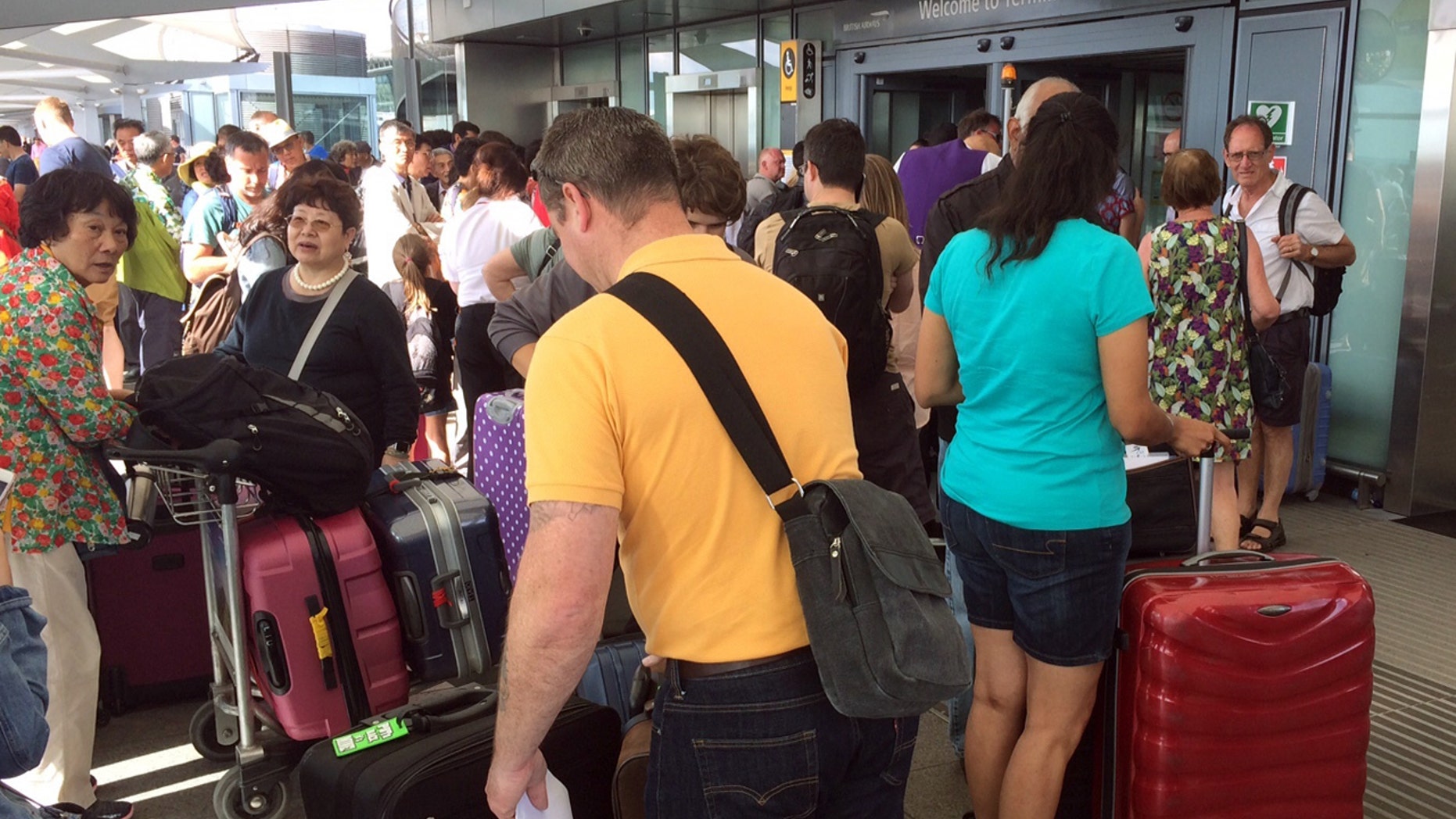 Passengers stand with their luggage outside Terminal 5 at London's Heathrow airport after flights were canceled due to the airport suffering an IT systems failure, Saturday, May 27, 2017.