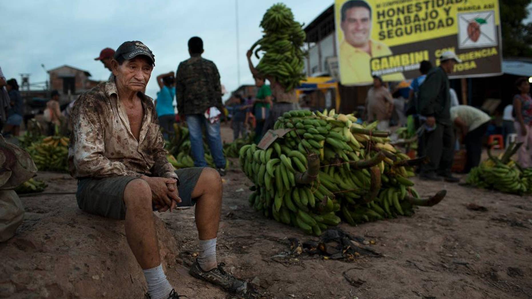 CHANGES OFFENSE TO MONEY LAUNDERING - In this Sept. 26, 2014 photo, a worker rests near a campaign banner that reads in Spanish; "Honesty, Jobs and Security," promoting gubernatorial candidate Manuel Gambini, in the port of Pucallpa, Peru. Gambini only entered the governor’s race in adjacent Ucayali state after a money laundering charge of the incumbent made national headlines, sidelining him. As two-term mayor of Irazola, a poor farming district where the Andes meet the Amazon, Gambini enriched himself, relatives and associates “closely tied to drug trafficking,” according to an eight-page order for a money laundering probe issued Aug. 29 and obtained by The Associated Press. (AP Photo/Rodrigo Abd)