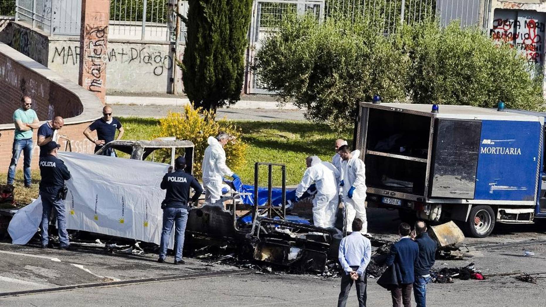 Forensic police recover a body from the a camper where three sister died, in Rome, Wednesday, May 10, 2017, when it burst into flames as they slept, in what news reports said might have been an intentional attack aimed at Roma, also known as Gypsies. Prosecutors have opened an arson investigation after surviving family members reported having received threats from local residents in recent days and another camper was torched last week nearby. The sisters aged 4, 8 and 20, were Roma and other family members who were in the camper at the time managed to escape. (Massimo Percossi/ANSA via AP)