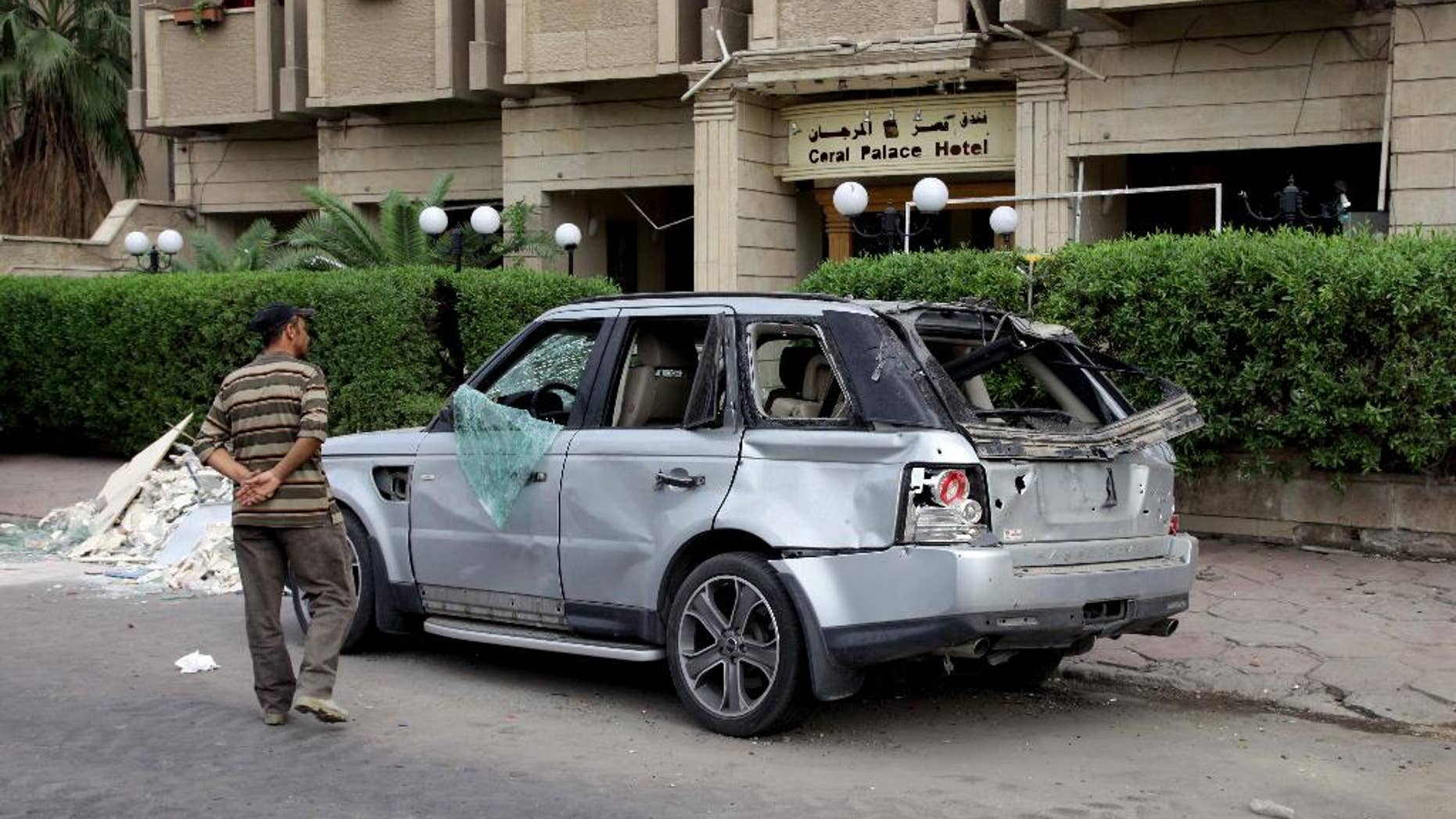 An Iraqi man inspects a damaged vehicle in the aftermath of a car bomb explosion in Baghdad, Iraq, Tuesday, Oct. 28, 2014. On Monday night, a car bomb blast near a line of shops and restaurants in downtown Baghdad killed more than a dozen and wounded tens, police said. (AP Photo/Khalid Mohammed)