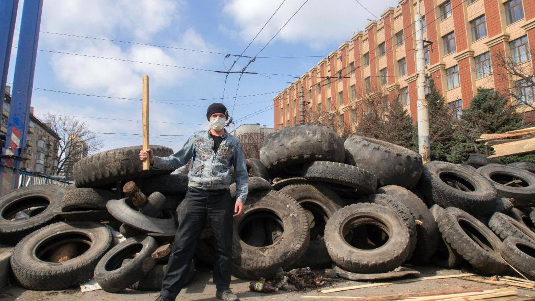 A masked pro-Russian activist poses for a photo in front of barricades at the Ukrainian regional office of the Security Service in Luhansk, 30 kilometers (20 miles) west of the Russian border, in Ukraine, Wednesday, April 9, 2014. Ukrainian Interior Minister Arsen Avakov said the standoff in Luhansk and the two neighboring Russian-leaning regions of Donetsk and Kharkiv must be resolved within two days.(AP Photo/Igor Golovniov)