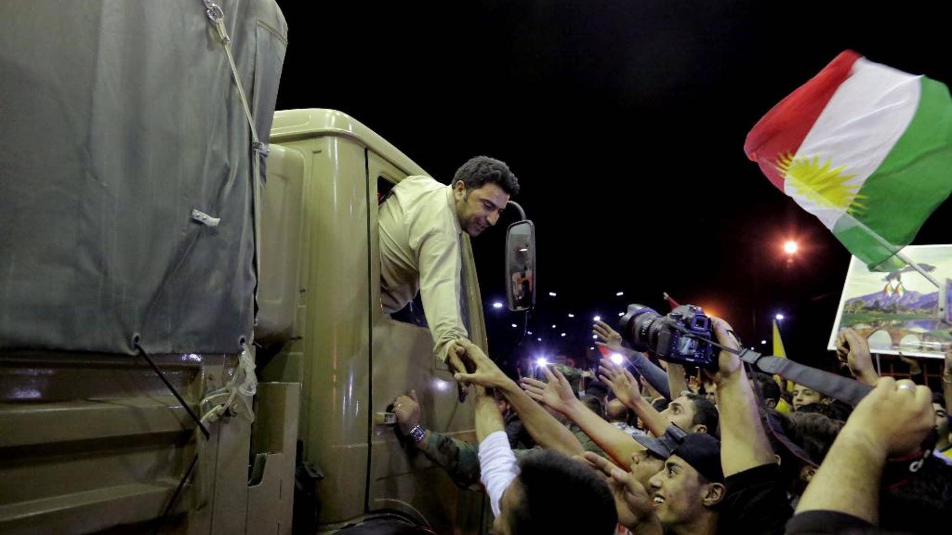 A Kurdish Peshmerga solider reaches out his hand to supporters, at the Ibrahim Khalil border crossing, in the Northern Kurdish Region of Iraq, Wednesday, Oct. 29, 2014. A group of Iraqi Kurdish peshmerga troops arrived in Turkey early Wednesday, on their way to Syria to help their Syrian Kurdish brethren fight Islamic State extremists in the embattled border town of Kobani. (AP Photo/Bram Janssen)