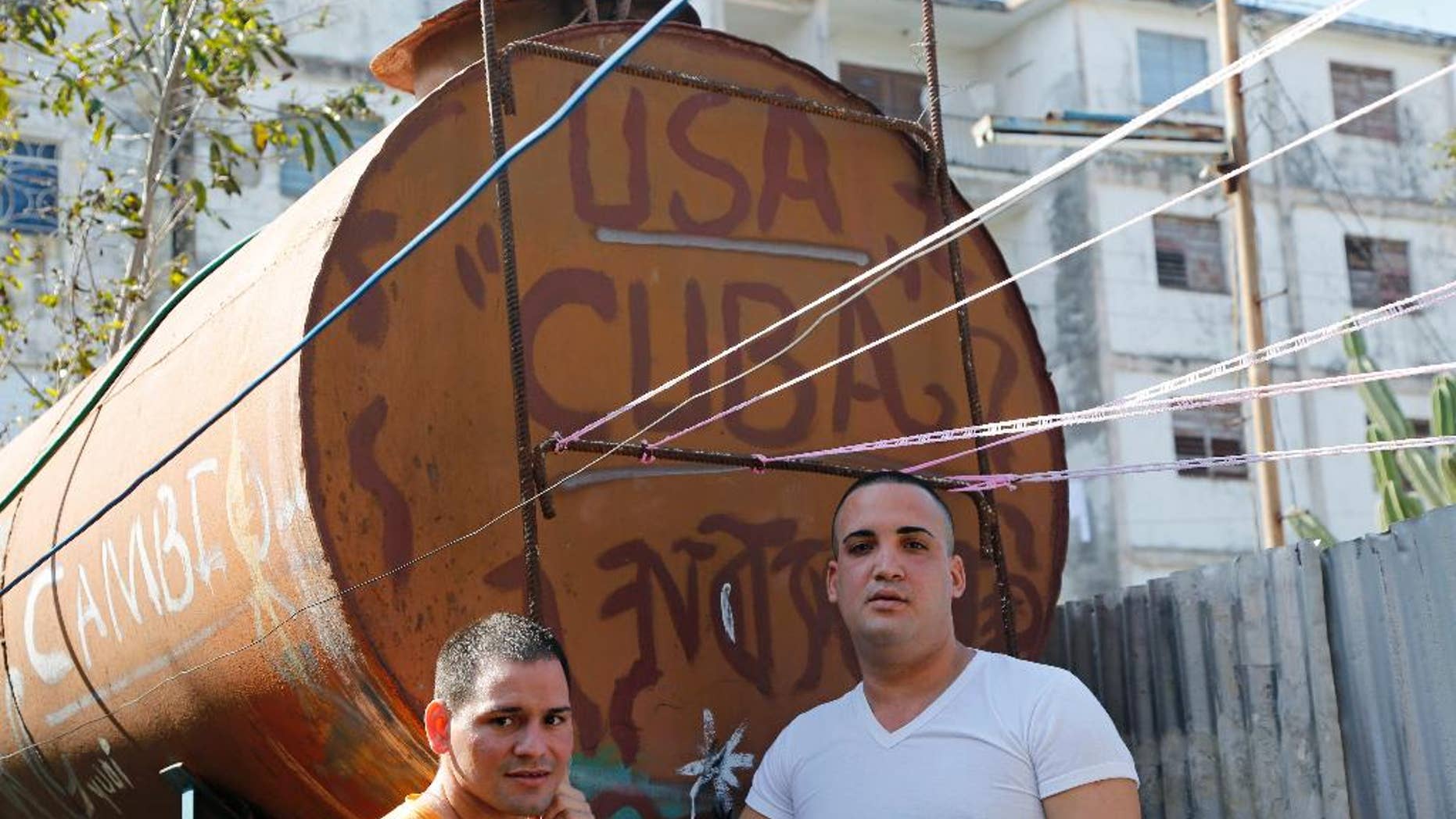 Freed Cuban dissidents Reinier Mulet, left, and Miguel Alberto Ulloa, stand beside a water tank in Havana, Cuba, Tuesday, Jan. 13, 2015. Ulloa and Mulet are two of 53 dissidents freed, most in the last week, as part of a U.S.-Cuban deal that also saw both countries liberate high-profile prisoners charged with espionage and move to normalize relations after five decades of tension. (AP Photo/Desmond Boylan)