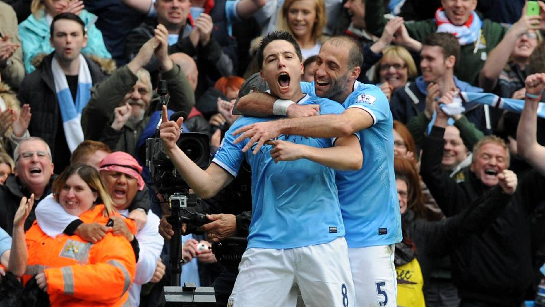 El francés Samir Nasri, del Manchester City, a la izquierda, celebra con el argentino Pablo Zabaleta tras anotar un gol contra el West Ham en la última fecha de la liga Premier, en el estadio Etihad, en Manchester, Inglaterra, el domingo 11 de mayo de 2014. El Man City se coronó el domingo campeón de la Premier. (AP Foto/Rui Vieira)