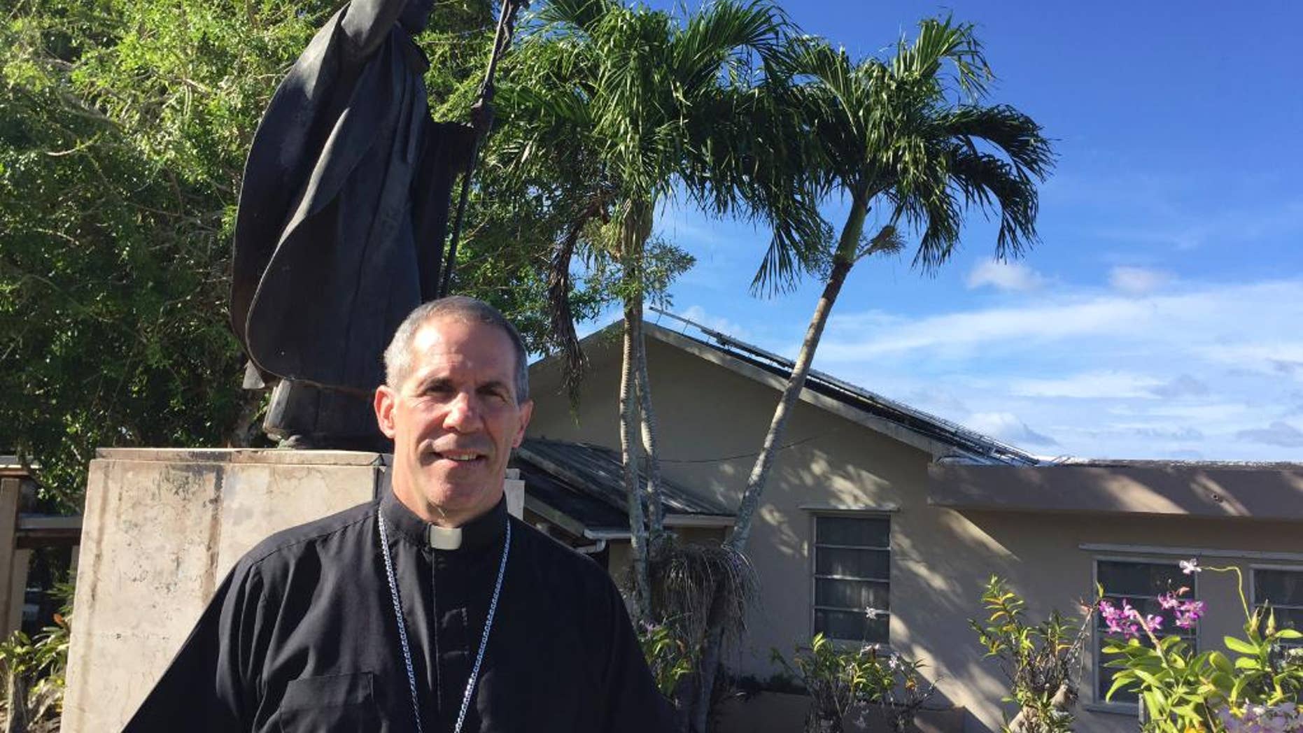 Archbishop Michael Byrnes poses for a photo in front of his residence in Hagatna, Guam, Friday, March 3, 2017. Byrnes, the current leader of Guam's Catholic Church, says financial settlements could be a good solution for the archdiocese, which is facing $115 million in civil lawsuits alleging child sexual abuse at the hands of priests. (AP Photo/Grace Garces Bordallo)