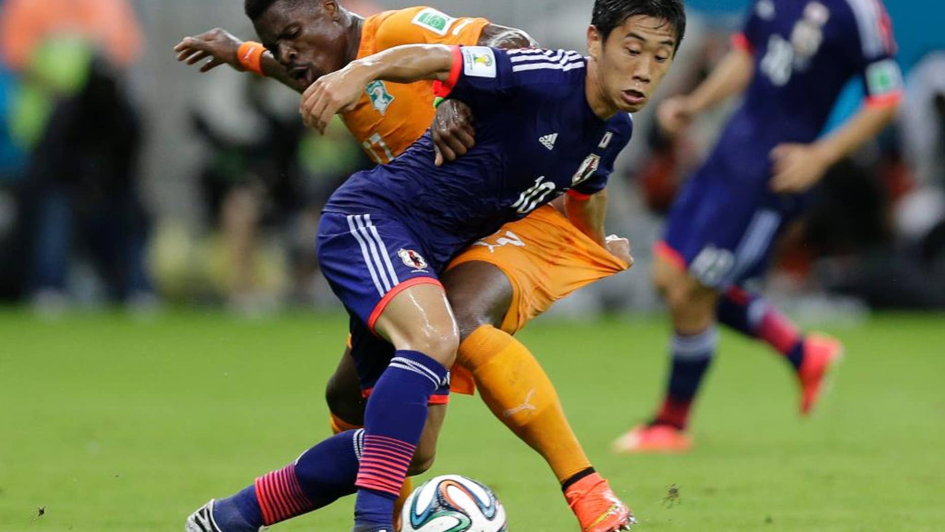 Japan's Shinji Kagawa, front, battles for the ball with Ivory Coast's Serge Aurier during the group C World Cup soccer match between Ivory Coast and Japan at the Arena Pernambuco in Recife, Brazil, Saturday, June 14, 2014. (AP Photo/Ricardo Mazalan)