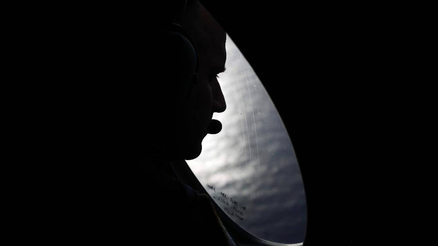 A Royal New Zealand Air Force crew member looks into the southern Indian Ocean from a P-3K2 Orion aircraft searches for missing Malaysian Airlines flight 370, Saturday, March 29, 2014. A day after the search for the Malaysian jetliner shifted to a new area of the Indian Ocean, ships on Saturday plucked objects from the sea to determine whether they were related to the missing jet. None were confirmed to be from the plane, leaving searchers with no sign of the jet three weeks after it disappeared. (AP Photo/Jason Reed, Pool)