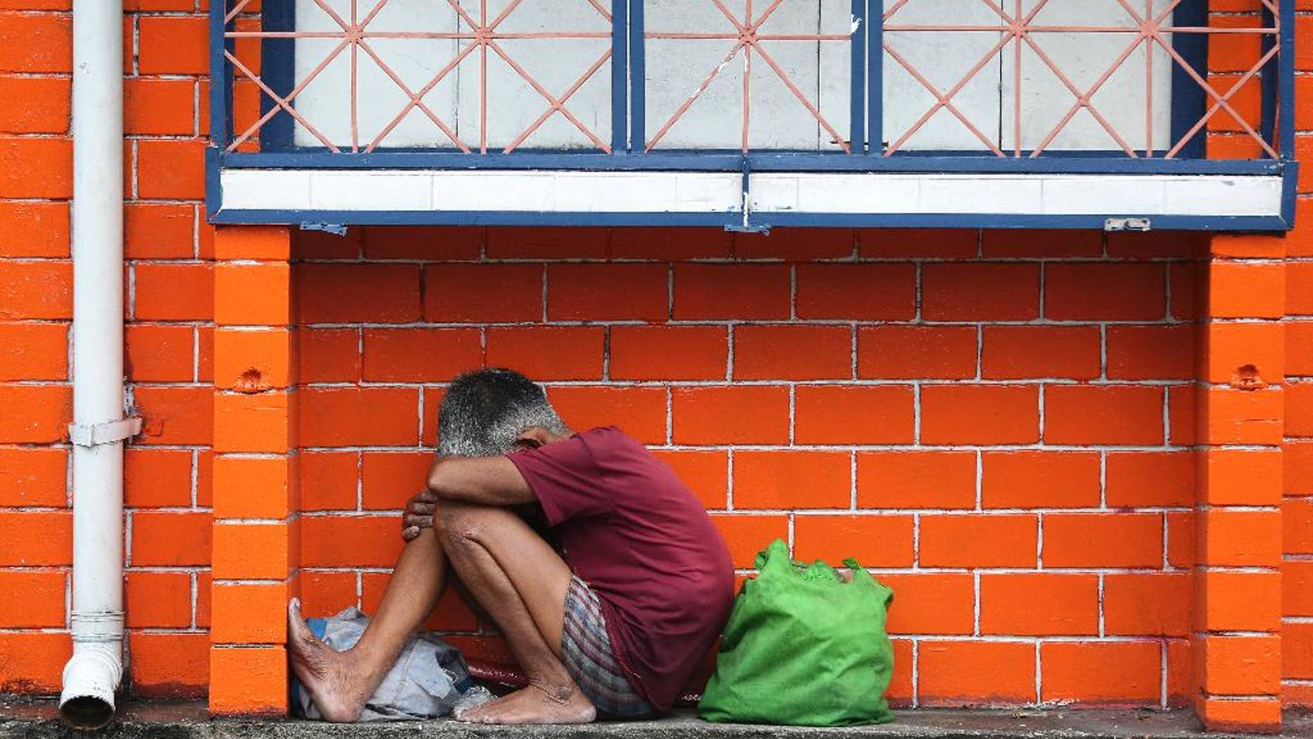 A Filipino woman takes shelter from rain caused by Typhoon Melor as the lowest level storm signal warning has been raised in Manila, Philippines Tuesday, Dec. 15, 2015. Typhoon Melor weakened Tuesday as it crossed over the central Philippines, leaving one man dead and wide areas without power. (AP Photo/Aaron Favila)
