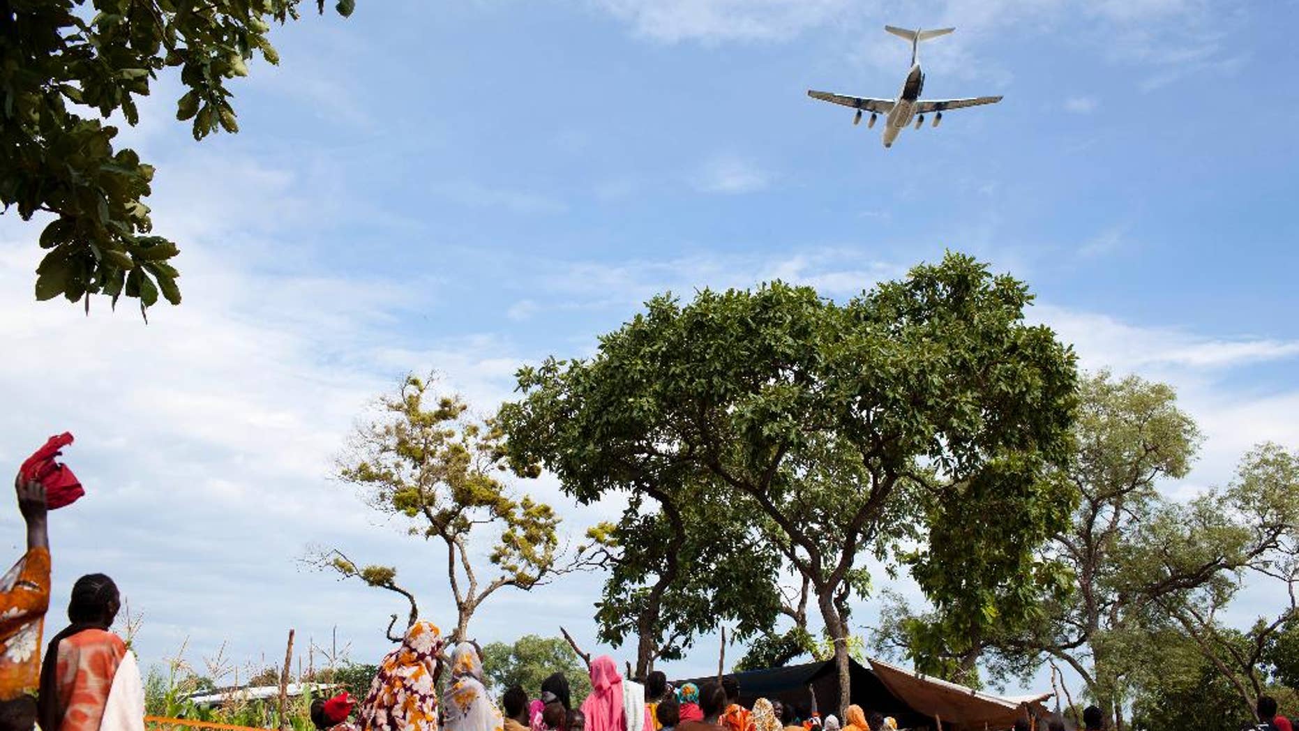 FILE - In this Friday, Sept. 14, 2012 file photo, a World Food Programme (WFP) aeroplane flies over a line of women and children waiting for a health screening, in Yida camp, South Sudan. WFP said Monday, Oct. 10, 2016 that South Sudan's government had suspended airdrops of food aid, the latest obstacle humanitarian officials have faced in this troubled country. (AP Photo/Mackenzie Knowles-Coursin, File)