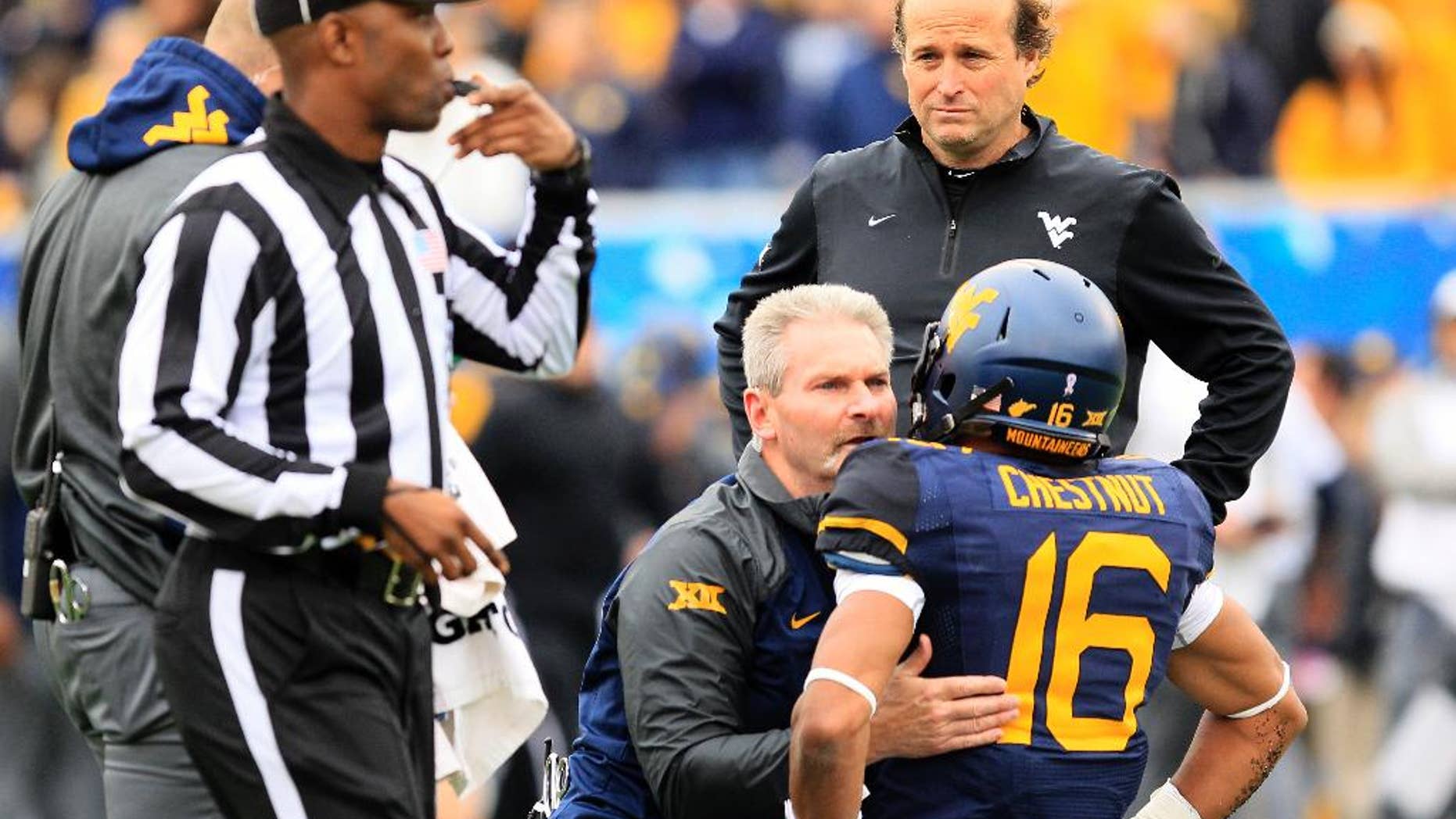 West Virginia coach Dana Holgorsen looks on as Terrell Chestnut (16) is looked over by the medical staff during the second half of an NCAA college football game against Baylor in Morgantown, W.Va., Saturday, Oct. 18, 2014. West Virginia won 41-27. Chestnut left the game with a concussion. (AP Photo/Chris Jackson)