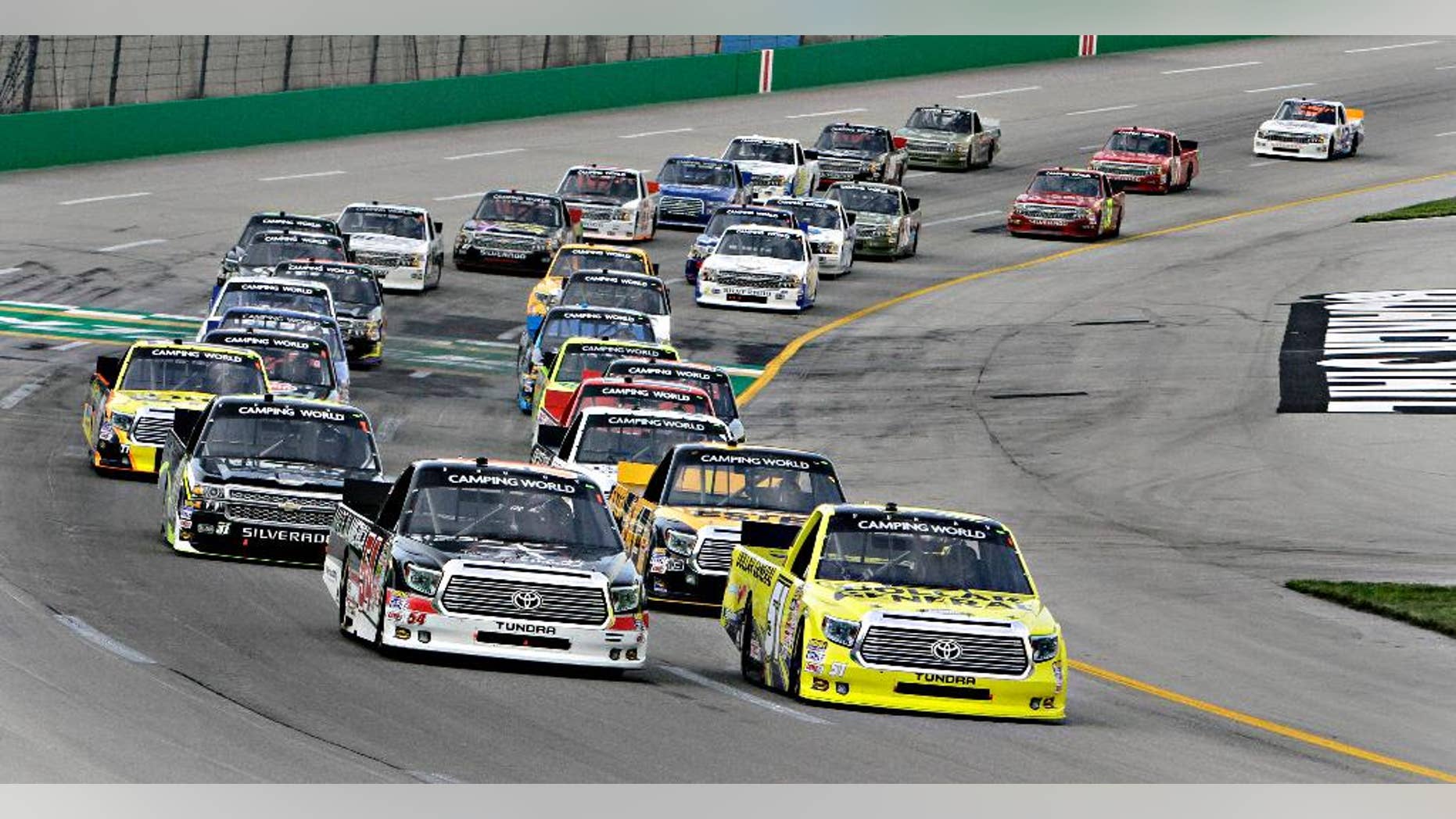 Pole-sitter Kyle Busch, right, leads the field into the first lap of the NASCAR Trucks auto race at Kentucky Speedway in Sparta, Ky., Thursday June 26, 2014. Darrell Wallace Jr. is at front left. (AP Photo/Garry Jones)