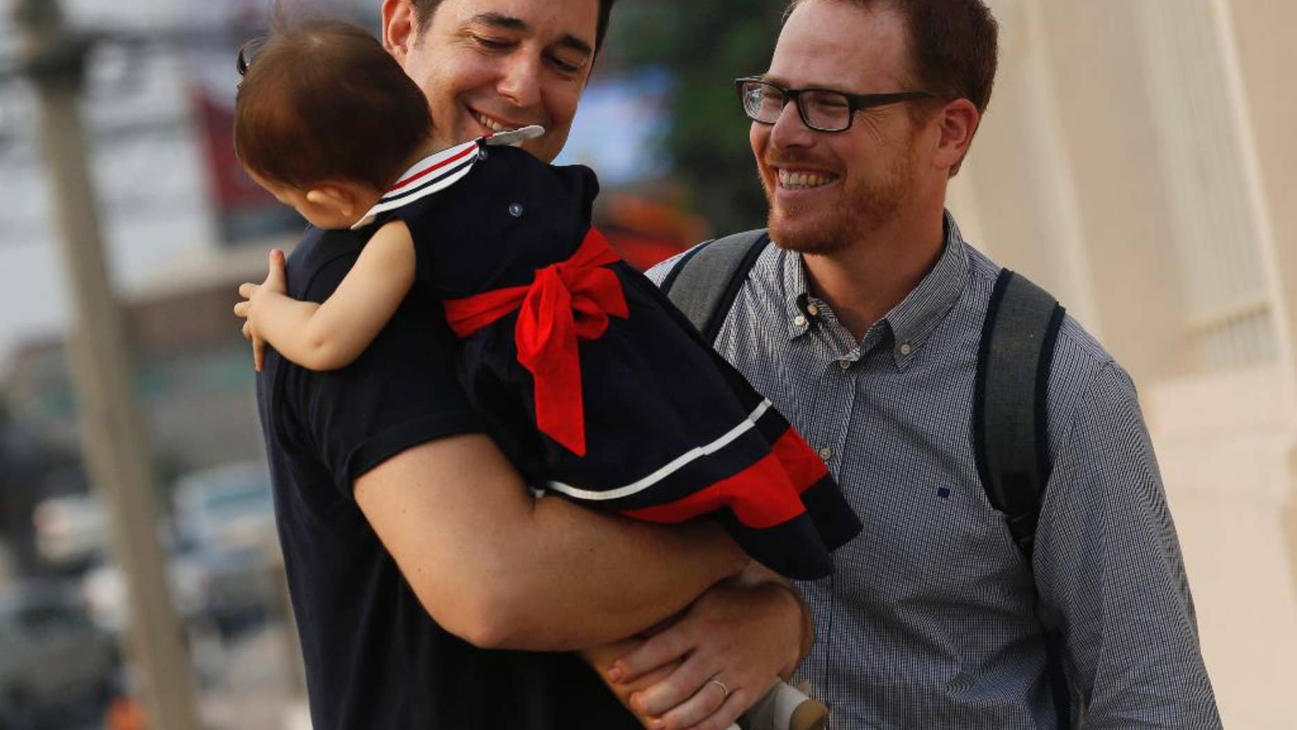 Manuel Santos, left, and Gordon Lake with their baby, Carmen, in March.