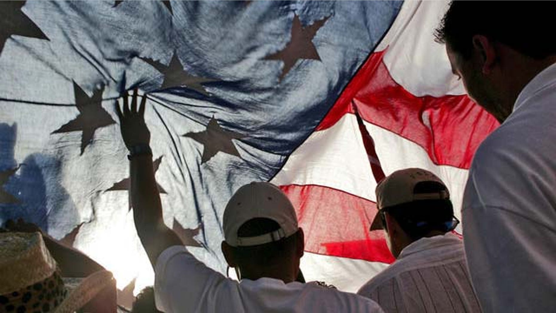 Immigration rights demonstrators hold a U.S. flag aloft during a march along Wilshire Boulevard, Monday, May 1, 2006, in Los Angeles. (AP Photo/Stefano Paltera)