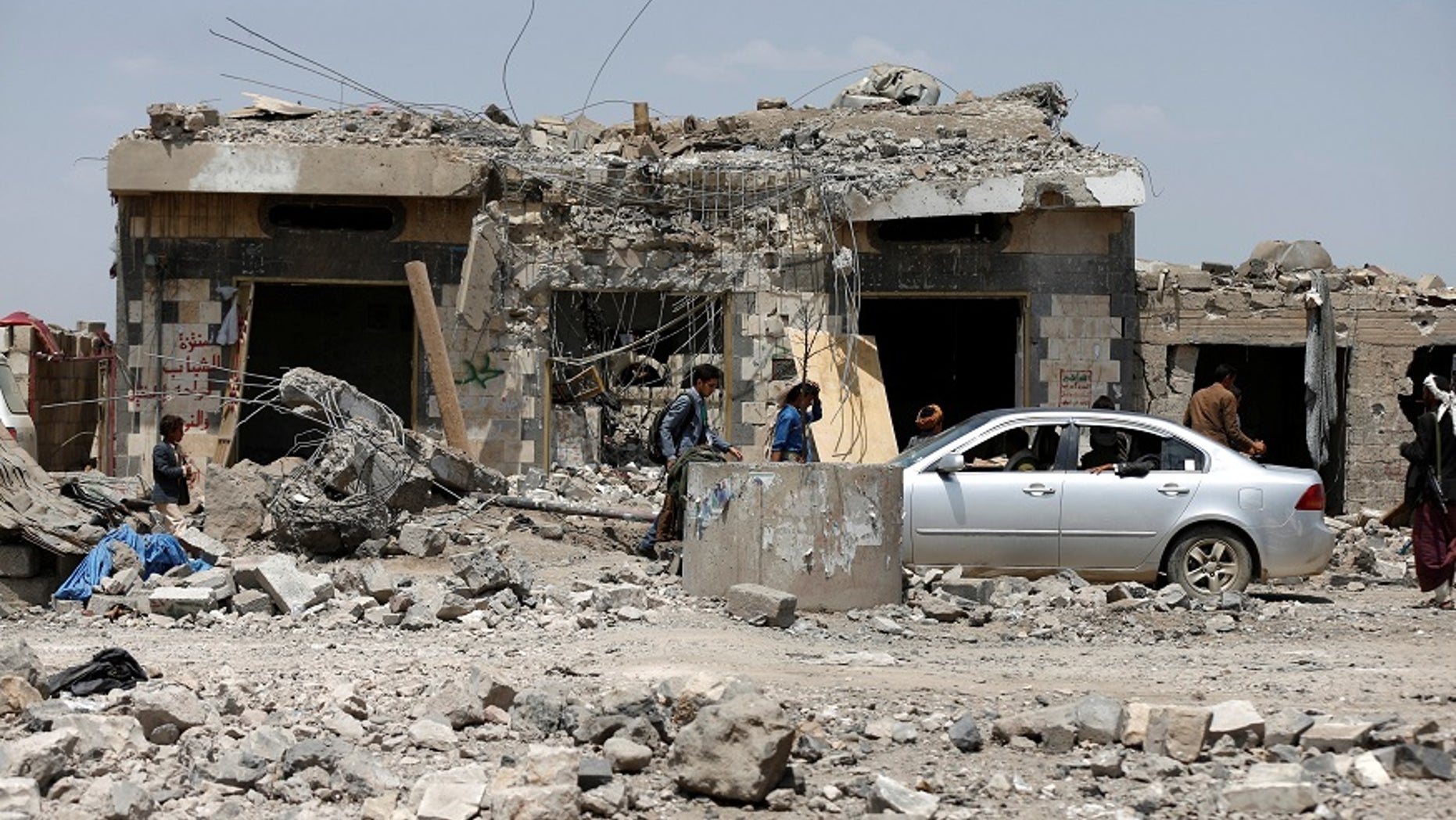 People walk to the site after a Saudi-led coalition airstrike in Arhab area, north of Sana'a, Yemen in August 2017