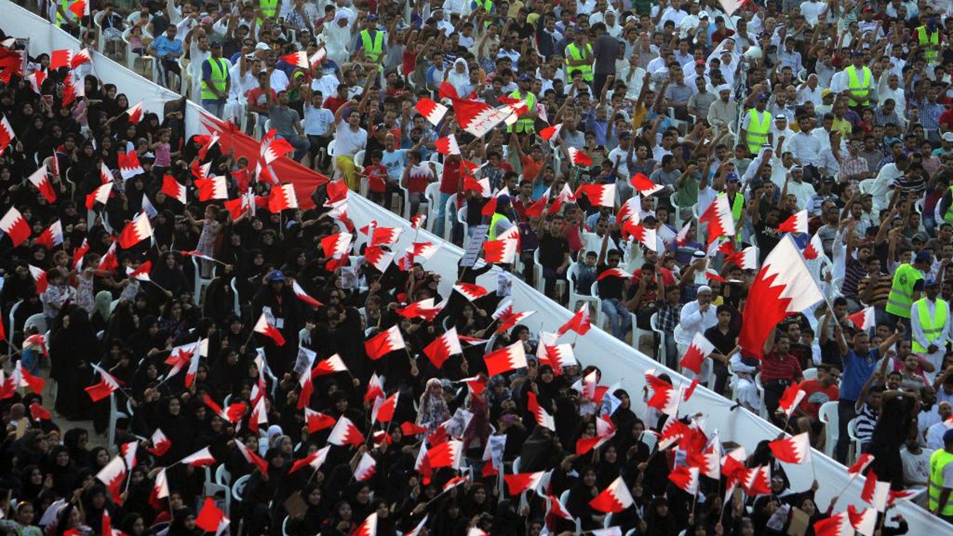 FILE- In this Friday, Sept. 30, 2011 file photo, Bahraini anti-government protesters wave flags and chant during a rally of thousands organized by Al-Wefaq, the largest Shiite opposition party, to demand greater freedoms in Quraya, Bahrain. Bahrain has again allowed agents of its domestic spy service to make arrests, reversing a key reform recommended in the wake of the crackdown that followed its 2011 Arab Spring protests. (AP Photo/Hasan Jamali, File)