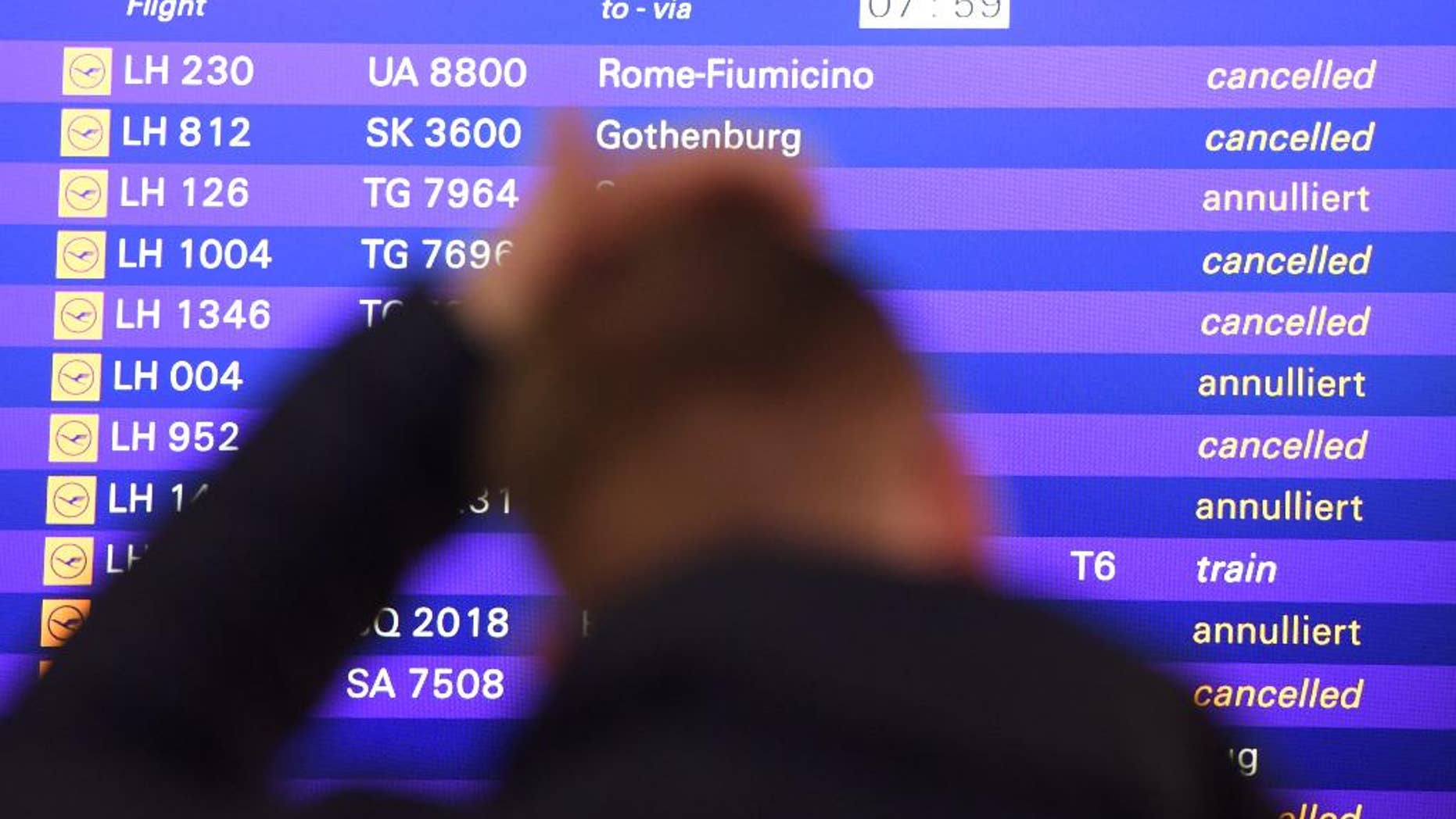 A passenger stands in front of the departure board at the airport in Frankfurt, Germany, Friday, Nov. 25, 2016. The Lufthansa pilots want to continue their strike at least until Saturday. (Arne Dedert/dpa via AP)
