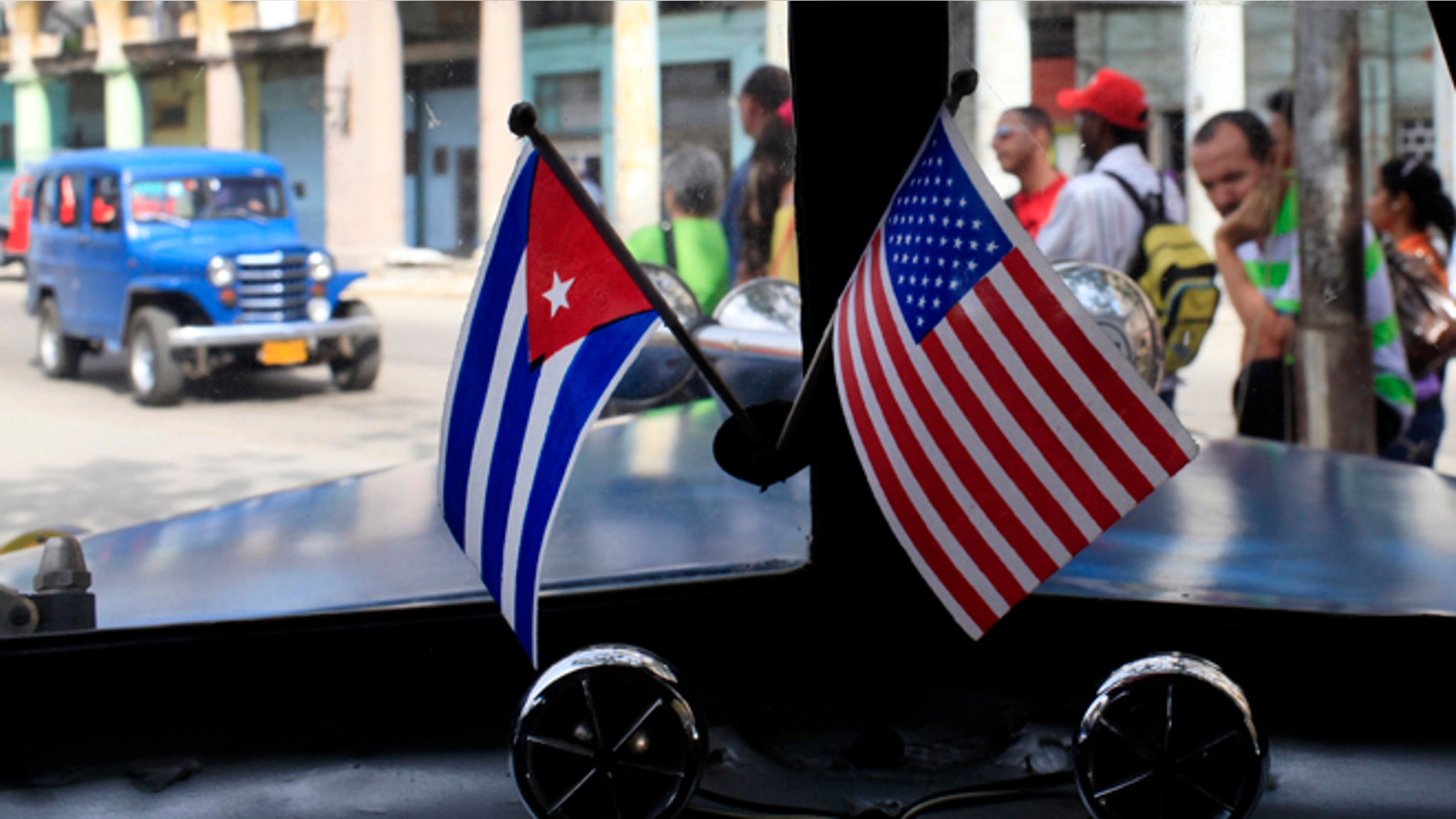 Miniature flags representing Cuba and the U.S. are displayed on the dash of an American classic car in Havana, Cuba, Friday, March 22, 2013. U.S. Secretary of State John Kerry must decide within a few weeks whether to advocate that President Barack Obama should take Cuba off a list of state sponsors of terrorism, a collection of Washington foes that also includes Iran, Syria and Sudan. Cuban officials have long seen the terror designation as unjustified and told visiting American delegations privately in recent weeks that they view Kerry's recommendation as a litmus test for improved ties. (AP Photo/Franklin Reyes)