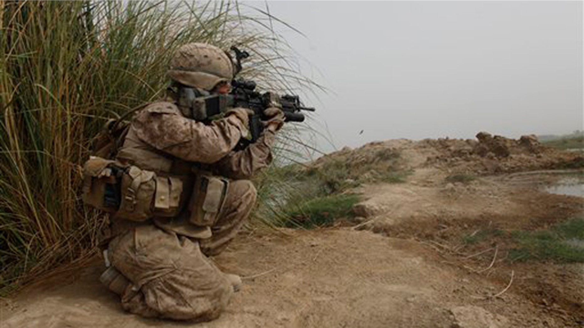 A U.S. Marine of 3rd Platoon, Kilo Company, 3/4 Marines, covers other Marines carrying boxes of U.S. Mail into their small outpost, Patrol Base 302, in Helmand province, southern Afghanistan, Friday, Aug. 26, 2011.