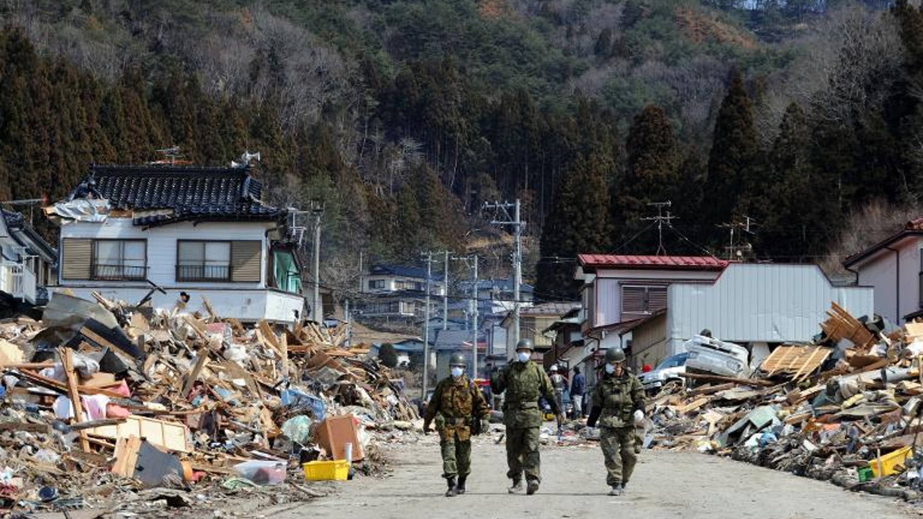 Japanese soldiers walk through the tsunami-destroyed town of Yamada, March 25, 2011. The government has suspended a senior official who blogged about the pointlessness of rebuilding tsunami-hit towns because they were populated mostly by old people.