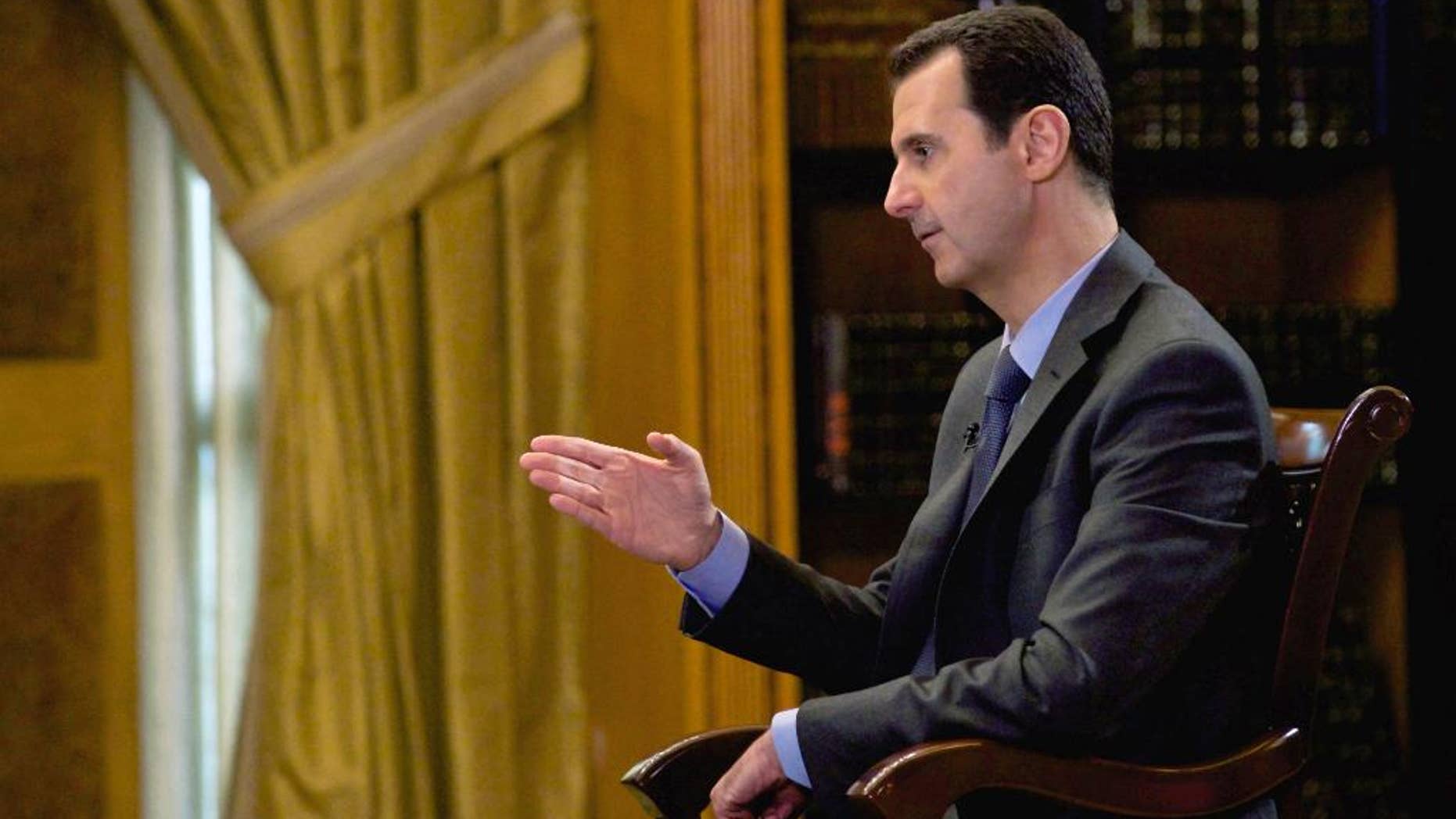 In this photo released Wednesday, March 4, 2015, by the Syrian official news agency SANA, Syrian President Bashar Assad speaks during an interview with Portuguese state television, RTP, in Damascus, Syria. Assad denied that his troops drop barrels bombs on civilians telling a journalist: "You are talking about massive propaganda." (AP Photo/SANA)