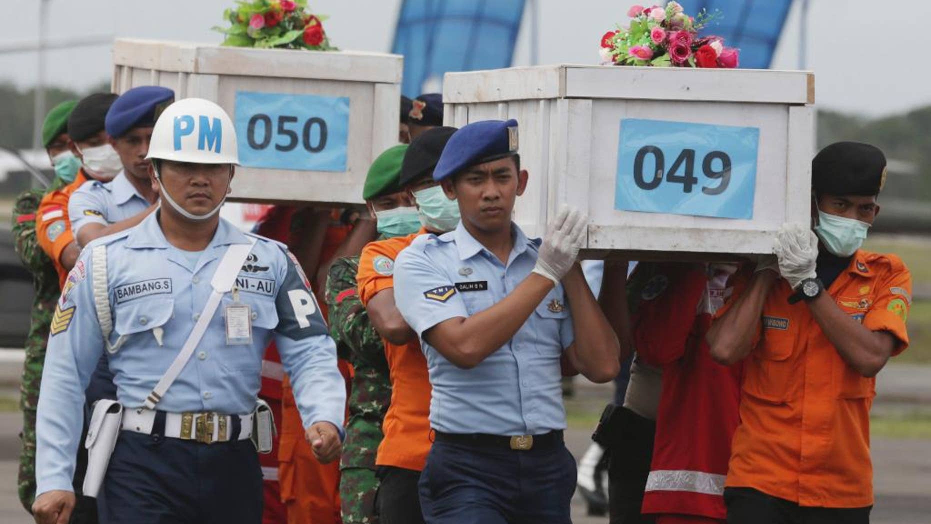 FILE - In this Monday, Jan. 19, 2015, file photo, members of the National Search and Rescue Agency carry coffins containing bodies of the victims aboard AirAsia Flight 8501 to transfer to Surabaya at the airport in Pangkalan Bun. The plane was climbing at an abnormally high rate, then plunged and suddenly disappeared from radar, Indonesia's transport minister said Tuesday, Jan. 20. (AP Photo/Achmad Ibrahim, File)