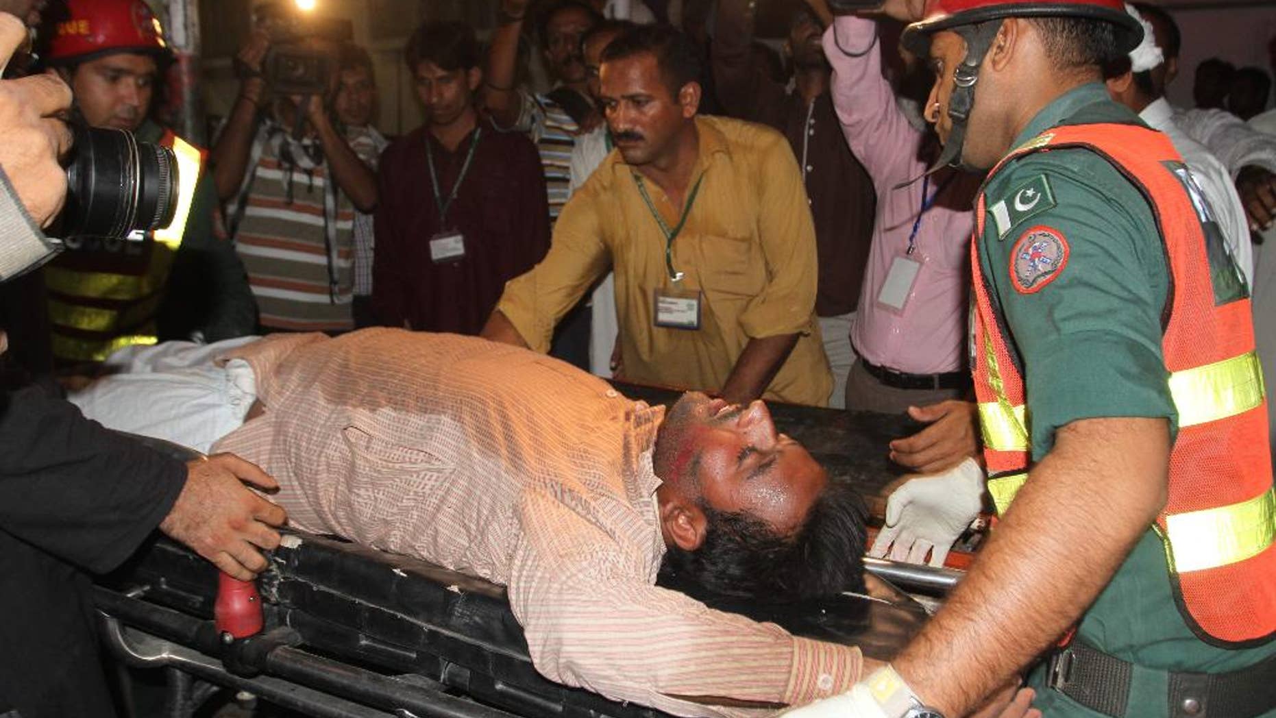 Pakistani rescue workers rush an injured person to a local hospital in Multan, Pakistan, Friday, Oct. 10, 2014. A stampede at a political rally of Pakistan's former cricketer turned politician, Imran Khan, left some scores of people dead and dozens more injured, police said. (AP Photo/Asim Tanveer)