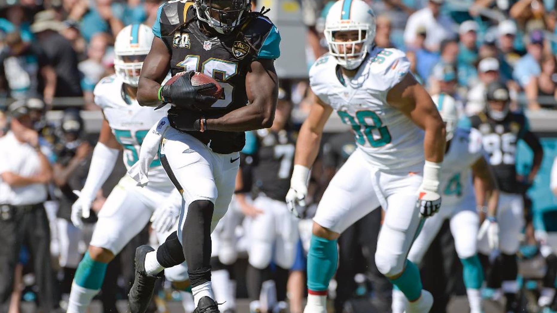 Jacksonville Jaguars running back Denard Robinson (16) takes off on a 41-yard run past Miami Dolphins defensive end Olivier Vernon, left, and defensive tackle Jared Odrick (98) during the first half of an NFL football game in Jacksonville, Fla., Sunday, Oct. 26, 2014. (AP Photo/Phelan M. Ebenhack)