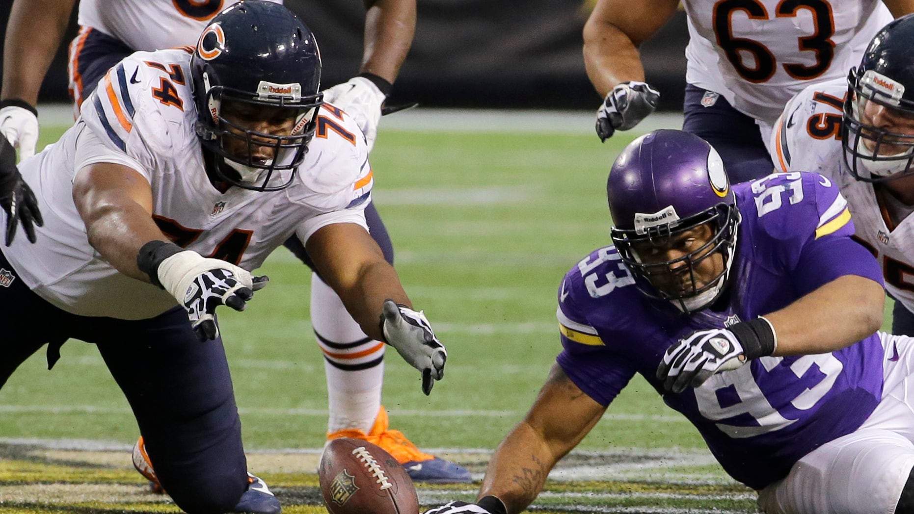 Chicago Bears tackle Jermon Bushrod, left, and Minnesota Vikings defensive tackle Kevin Williams, right, eye a fumble during the fourth quarter of an NFL football game on Sunday, Dec. 1, 2013, in Minneapolis. The Vikings won 23-20 in overtime. (AP Photo/Ann Heisenfelt)