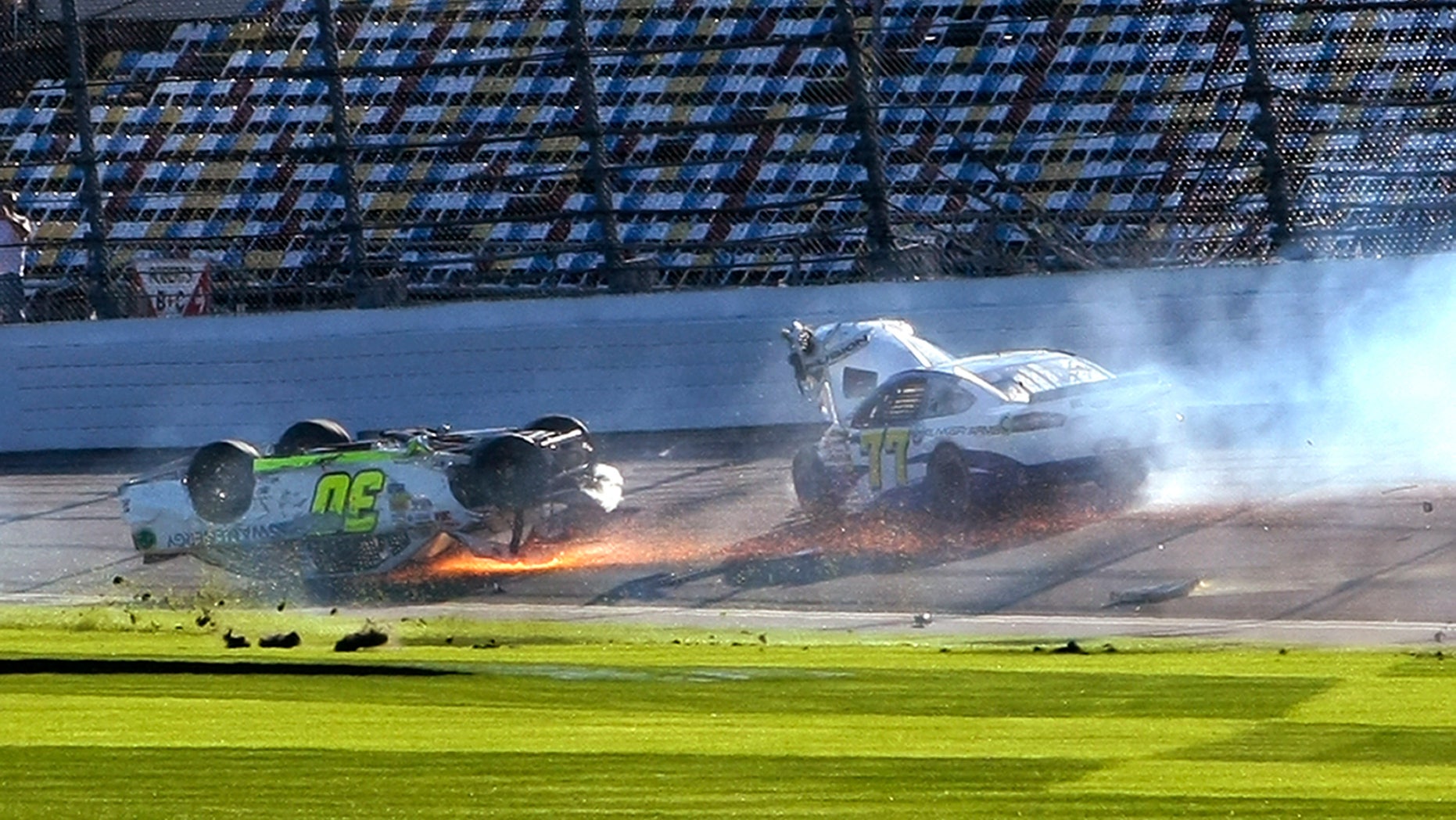 Parker Kligerman (30) slides upside down through the front stretch as Dave Blaney (77) goes around after a crash during a practice session for the NASCAR Daytona 500 auto race at Daytona International Speedway in Daytona Beach, Fla., Wednesday, Feb. 19, 2014. (AP Photo/Alex Menendez)