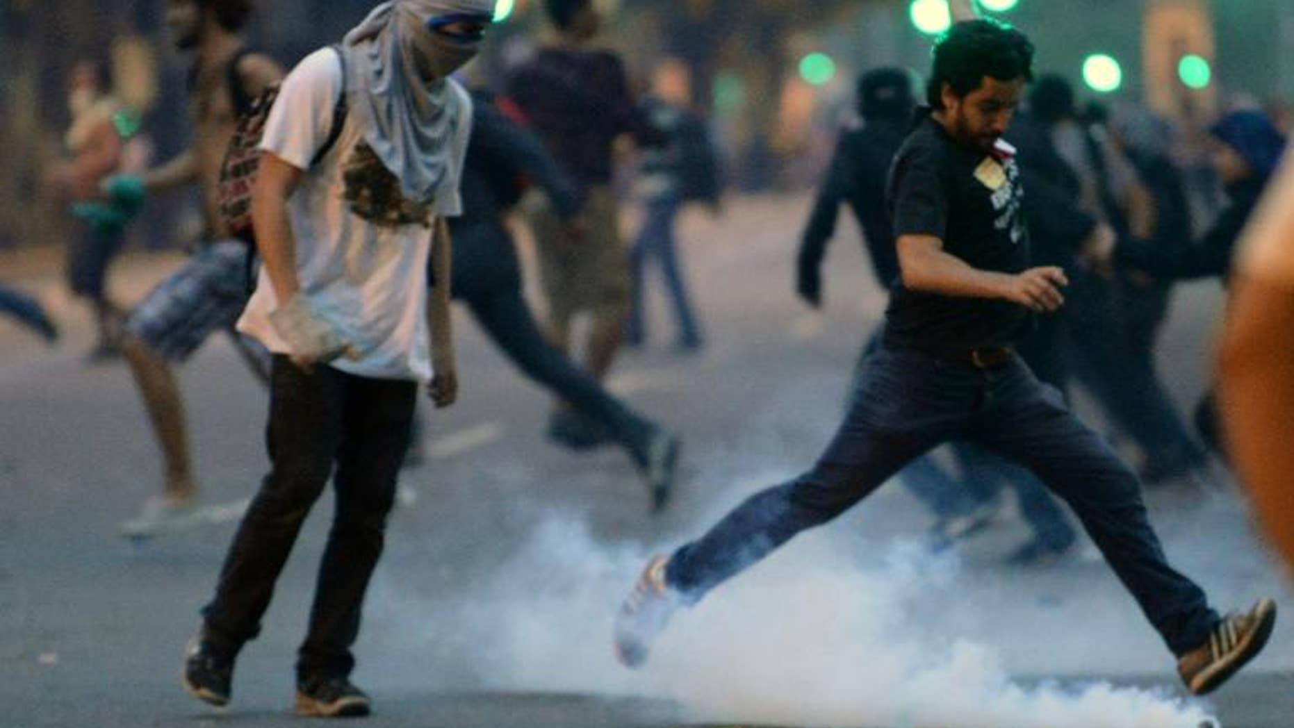A demonstrator kicks a tear gas grenade during a protest by teachers in Rio de Janeiro, Brazil, on October 1, 2013