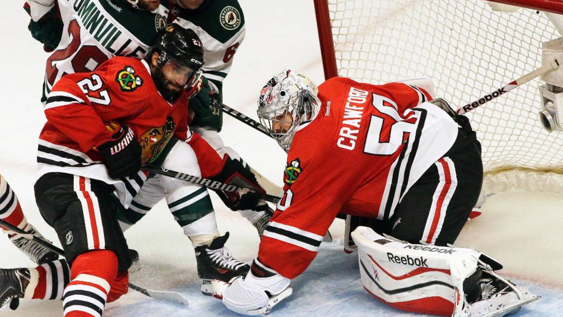 Chicago Blackhawks goalie Corey Crawford (50) blocks a shot as Johnny Oduya (27) battles for the puck against Minnesota Wild's Jason Pominville (29) and Mikael Granlund (64) during the third period in Game 5 of an NHL hockey second-round playoff series in Chicago, Sunday, May 11, 2014. The Blackhawks won 2-1. (AP Photo/Nam Y. Huh)
