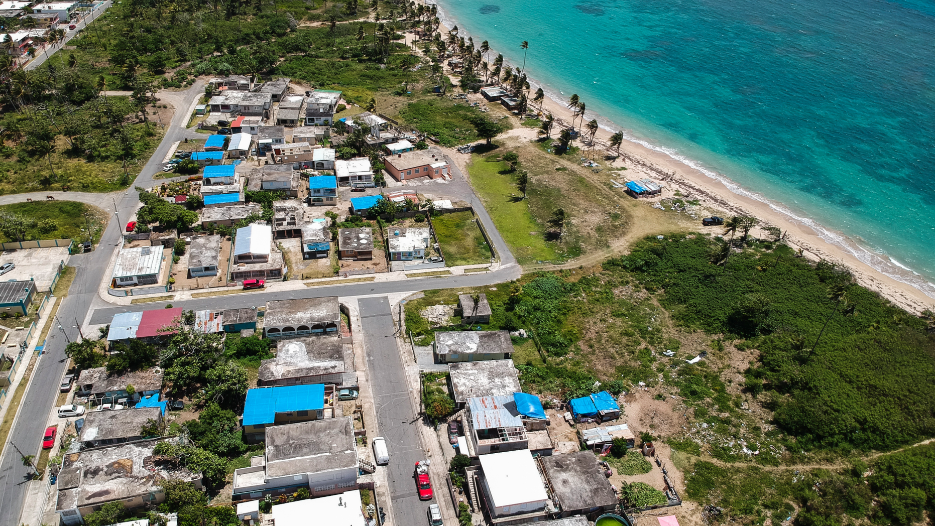 FILE - This June 18, 2018 file photo shows an aerial photo of the Viequez neighborhood, east of San Juan, Puerto Rico, where people were still living in damaged homes, protected by blue plastic tarps, nine months since Hurricane Maria devastated the island. Puerto Rico's governor said on Tuesday, Sept. 11, 2018 that his administration has adopted new measures to better prepare for a disaster like Maria while he warned of limitations given the U.S. territory's economic crisis. (AP Photo/Dennis M. Rivera, File)