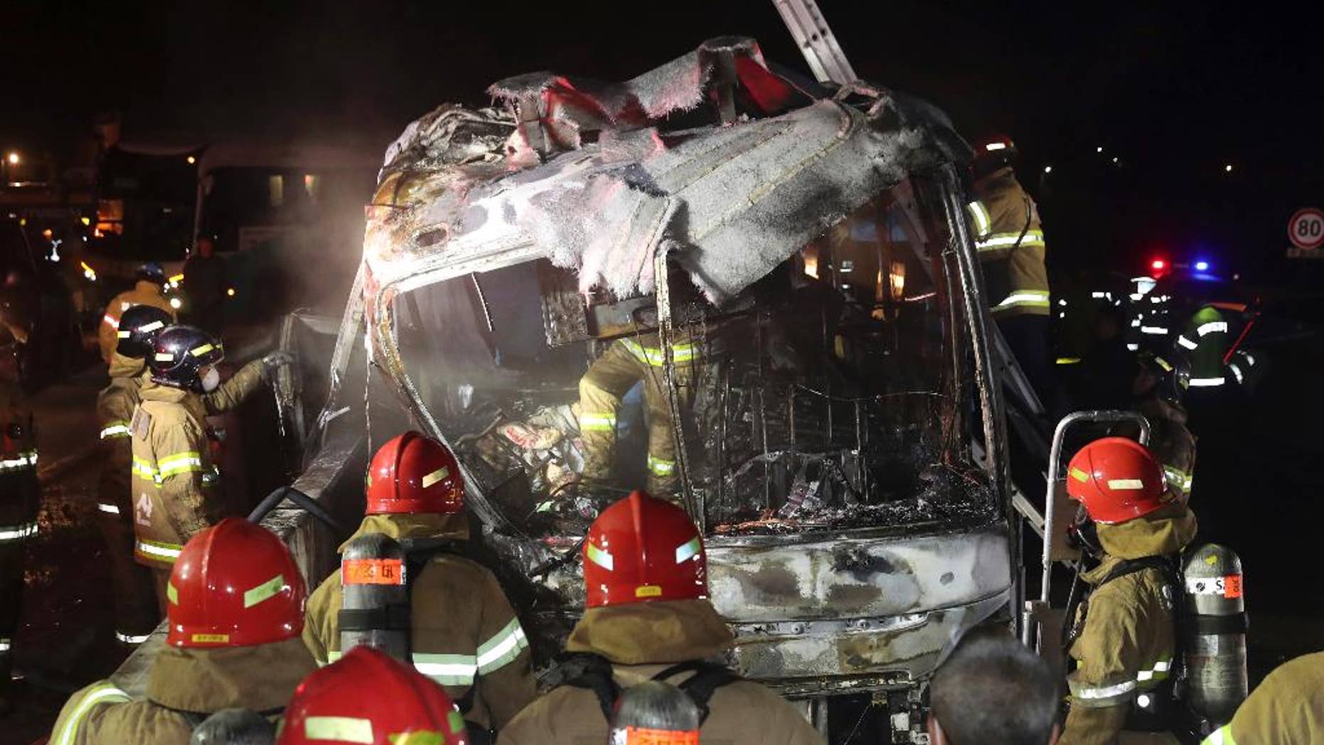 South Korean firefighters check a burned out bus on the Gyeongbu Expressway near the southeastern city of Ulsan, South Korea, Friday, Oct. 14, 2016. Twenty people, including the driver, were on the bus when it smashed into the guardrail and caught fire on the expressway, officials said. (Kim Yong-tae/Yonhap via AP) KOREA OUT